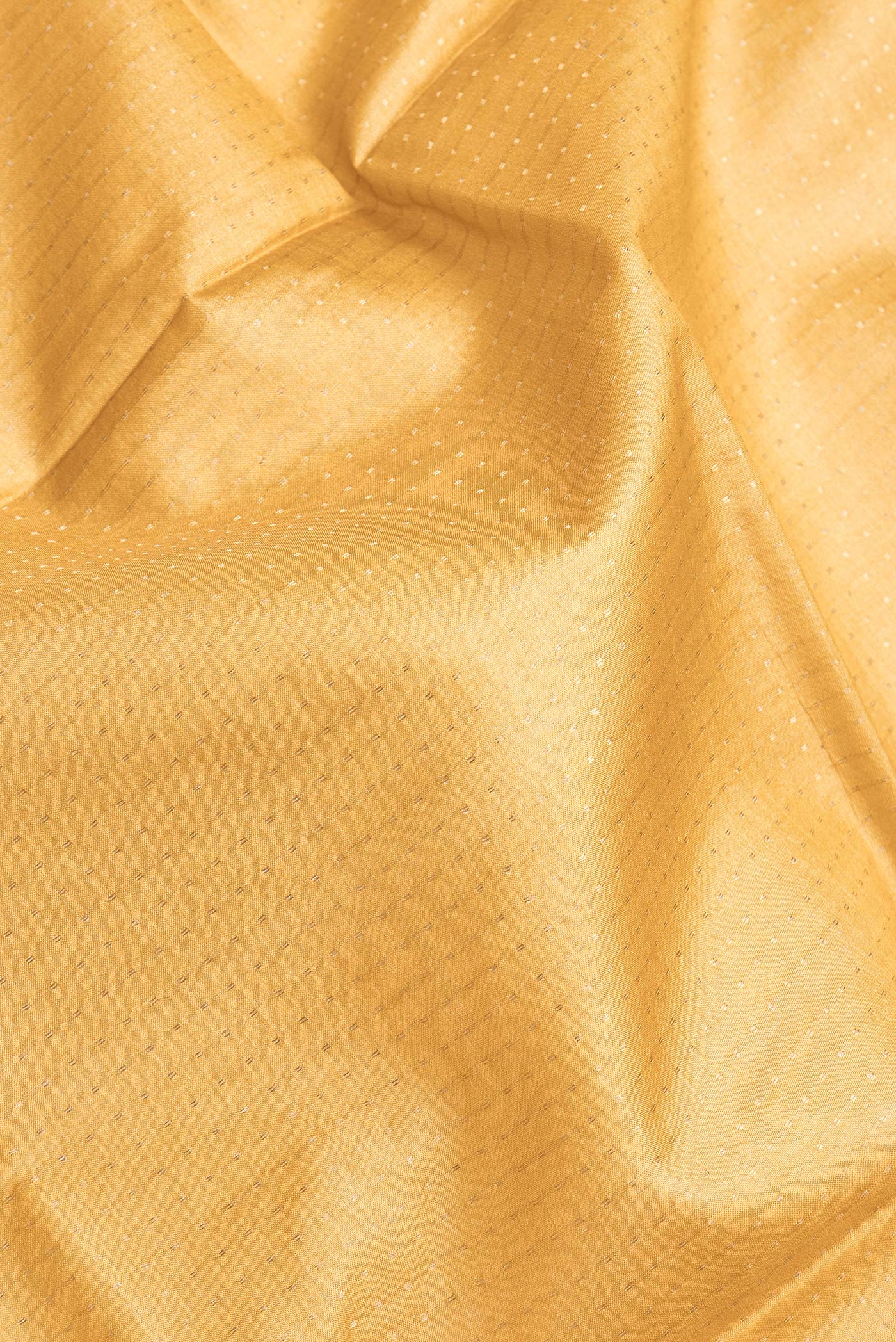 Close up of Mustard Dual Tone Tussar Silk Saree with Zari Butta on the body and Printed Border.  displaying folds