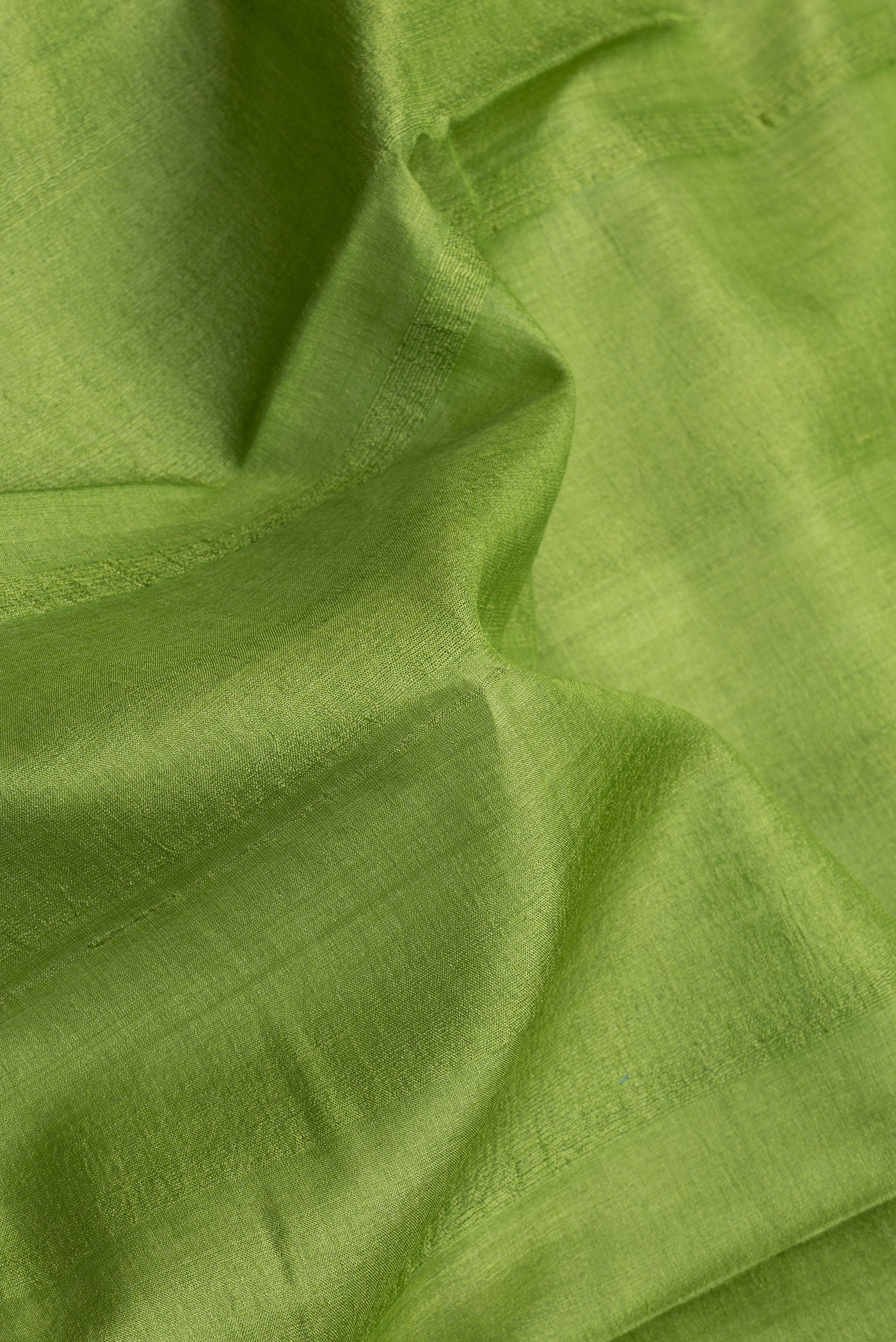 Close up of Parrot Green Dual Tone Tussar Silk Saree with Plain Body and Printed Border.  displaying folds