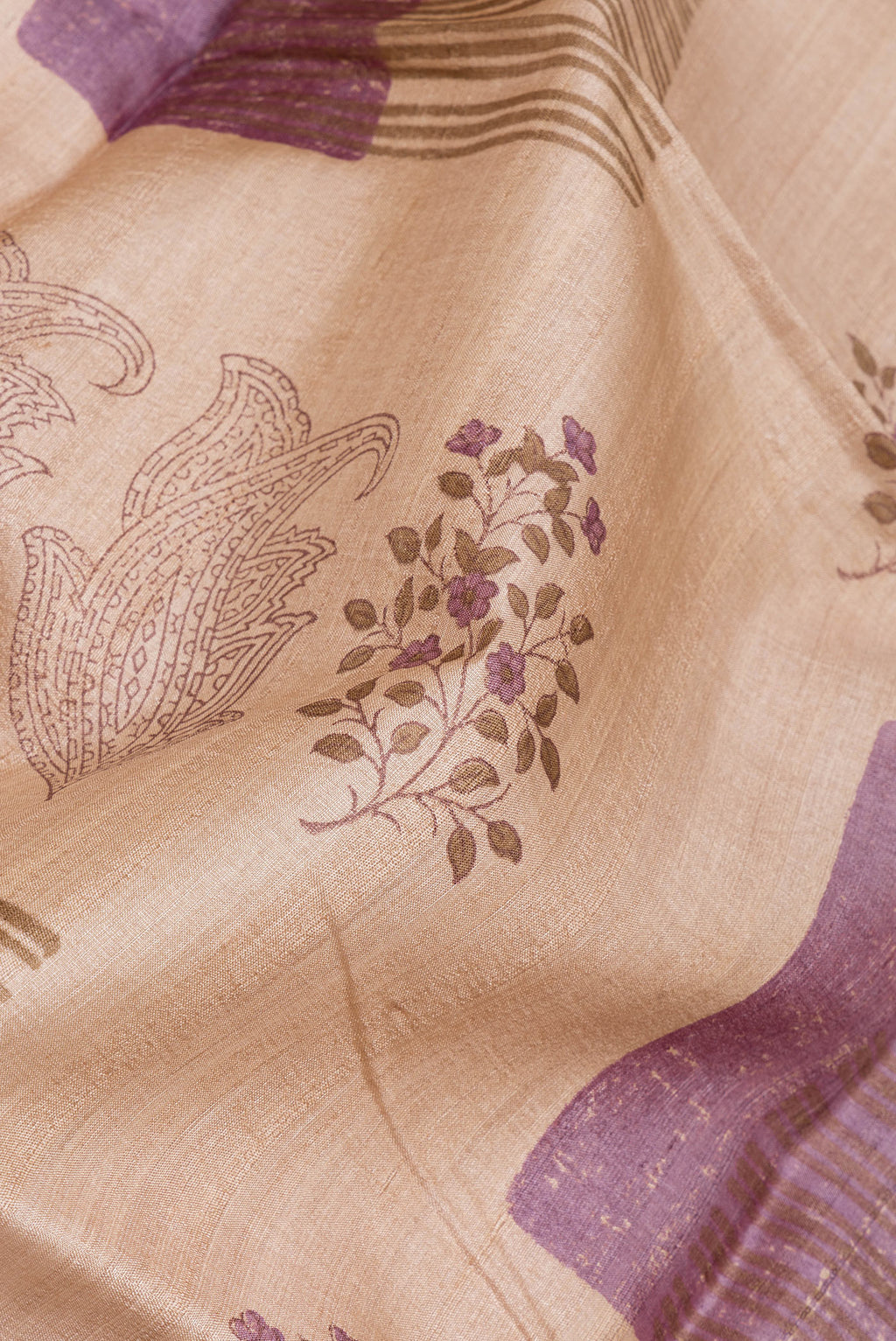 Close up of Beige Tussar Silk Saree with Printed design on the body and Fancy Border.  displaying folds