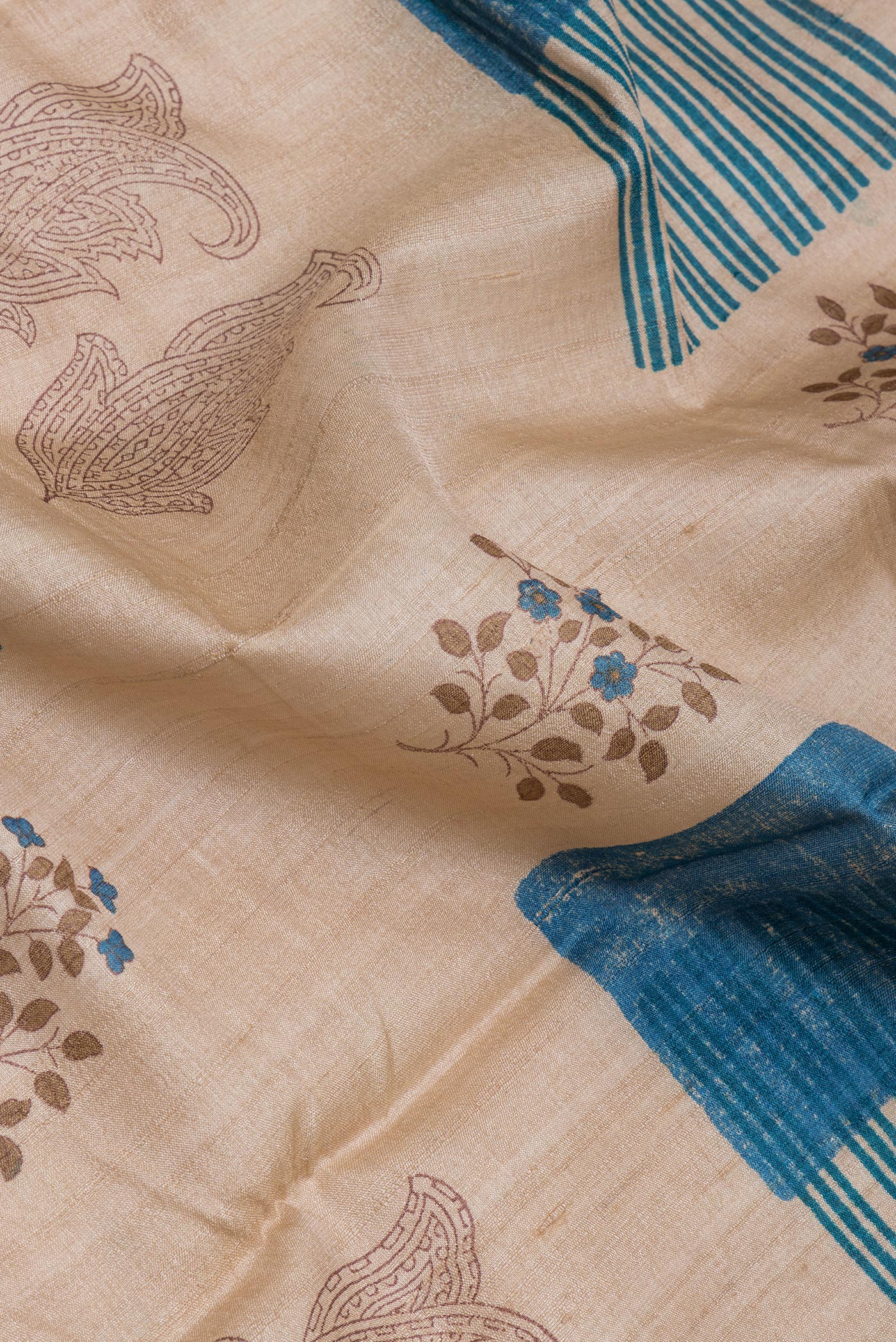 Close up of Beige Tussar Silk Saree with Printed design on the body and Printed Border.  displaying folds