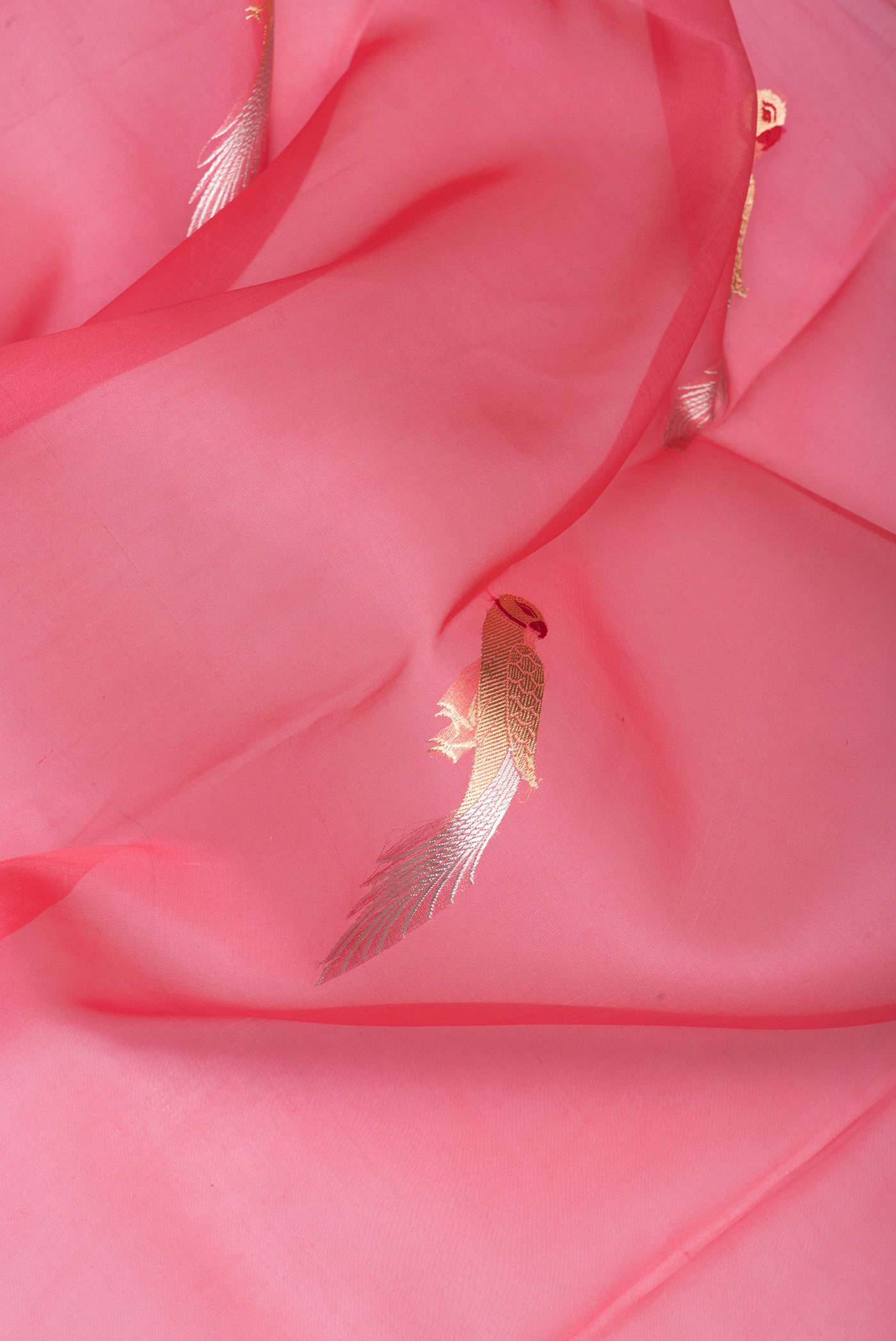 Close up of Peach Organza Silk Saree with Zari And Thread Butta on the body and Zari Border.  displaying folds