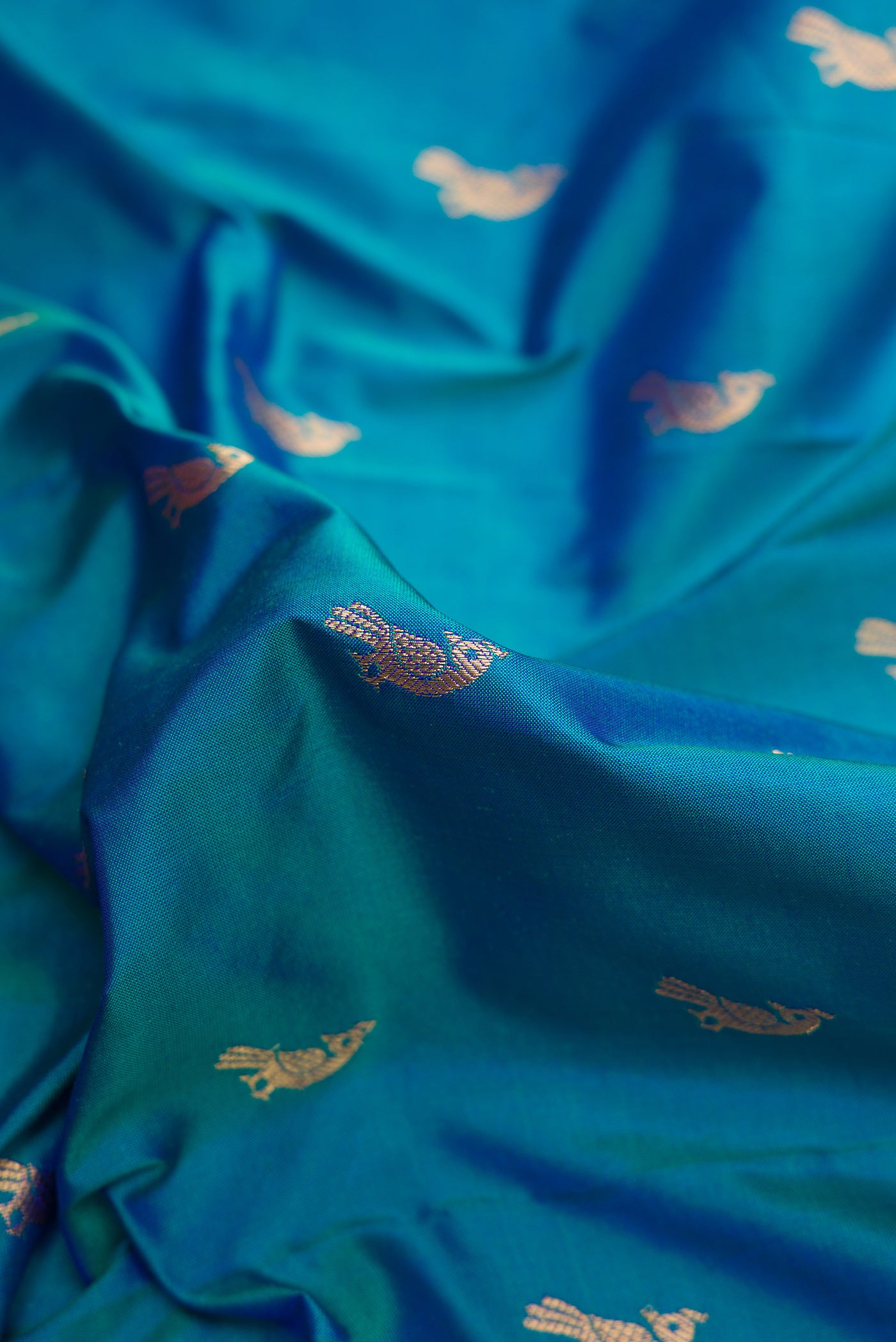 Close up of Peacock Blue Dual Tone Paithani Silk Saree with Zari Butta on the body and Paithani Border.  displaying folds