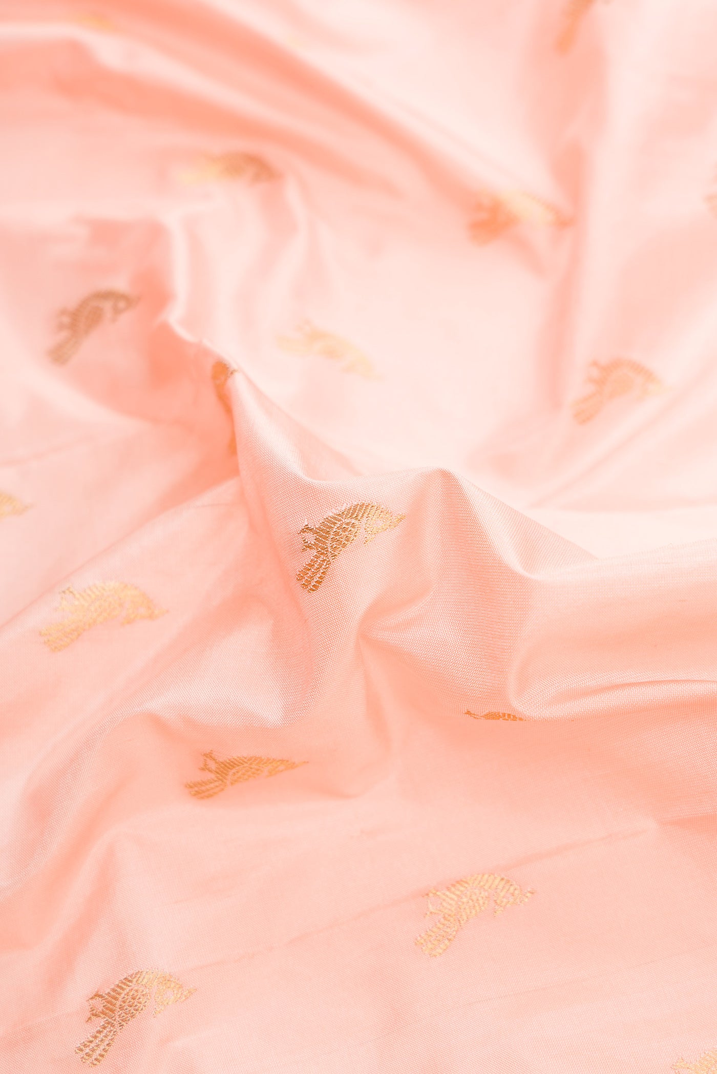 Close up of Peach Dual Tone Paithani Silk Saree with Zari Butta on the body and Paithani Border.  displaying folds