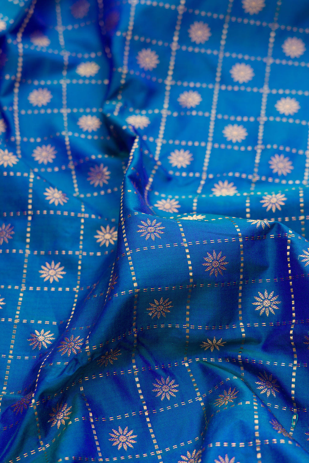 Close up of Pure Silk Peacock Blue Dual Tone Paithani Saree with Checked design on the body and Paithani Border.  displaying folds