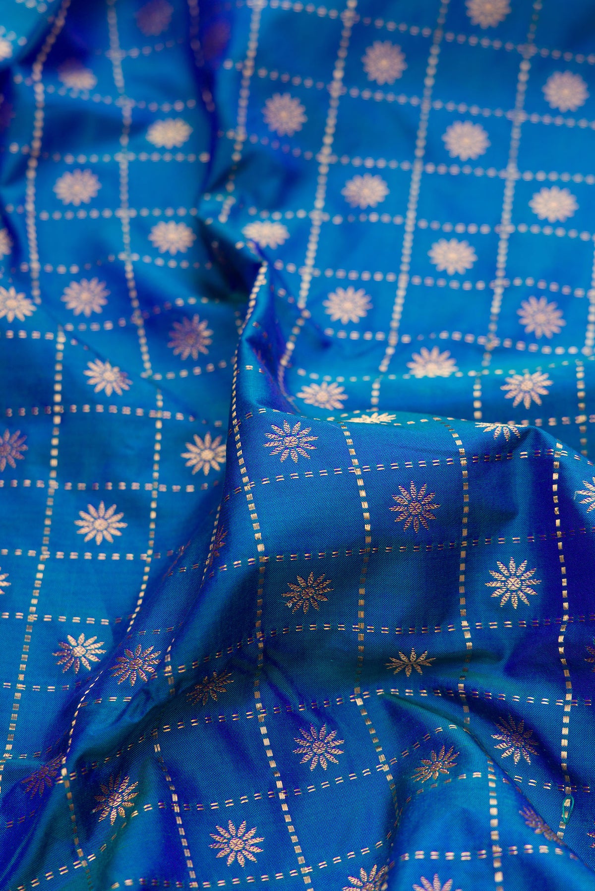 Close up of Pure Silk Peacock Blue Dual Tone Paithani Saree with Checked design on the body and Paithani Border.  displaying folds