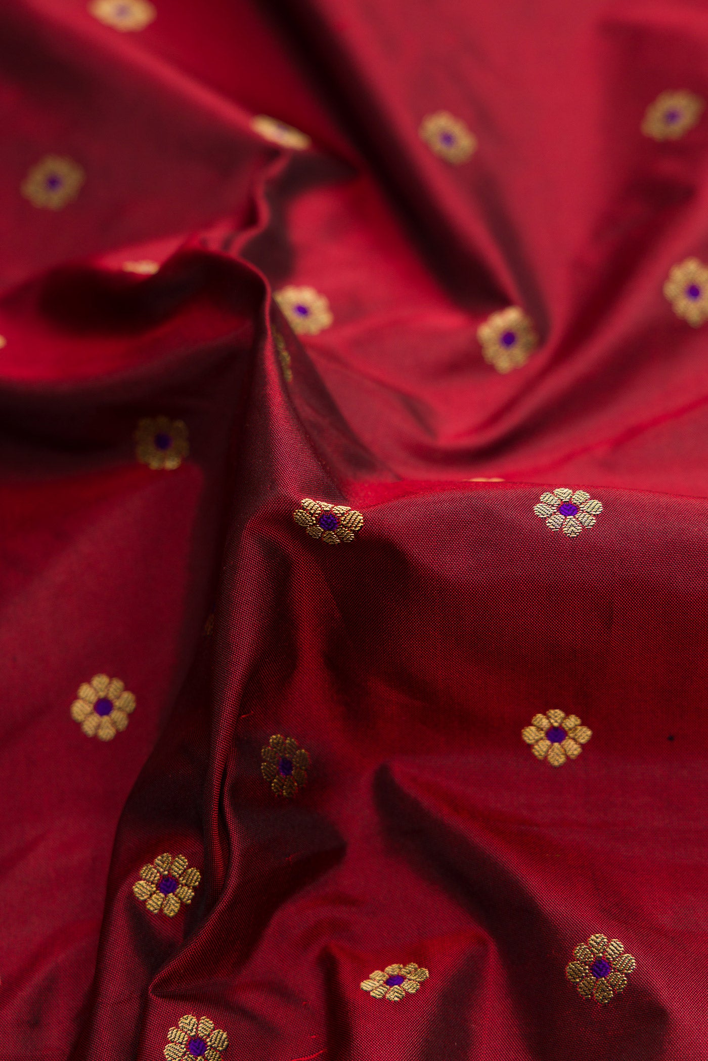 Close up of Maroon Dual Tone Paithani Silk Saree with Zari Butta on the body and Paithani Border.  displaying folds