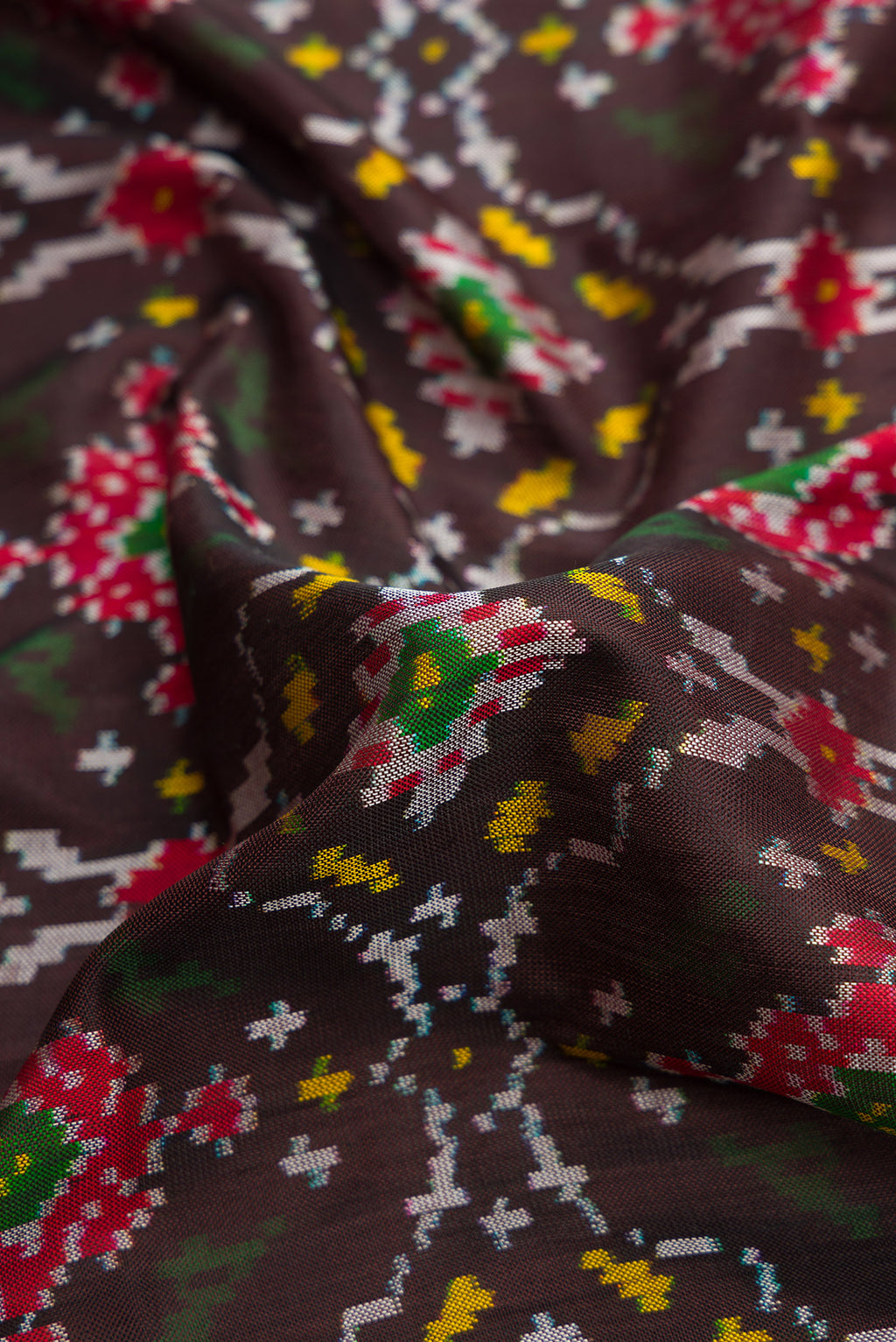 Close up of Black Dual Tone Double Ikat Saree with Ikat Print on the body and Thread Border.  displaying folds