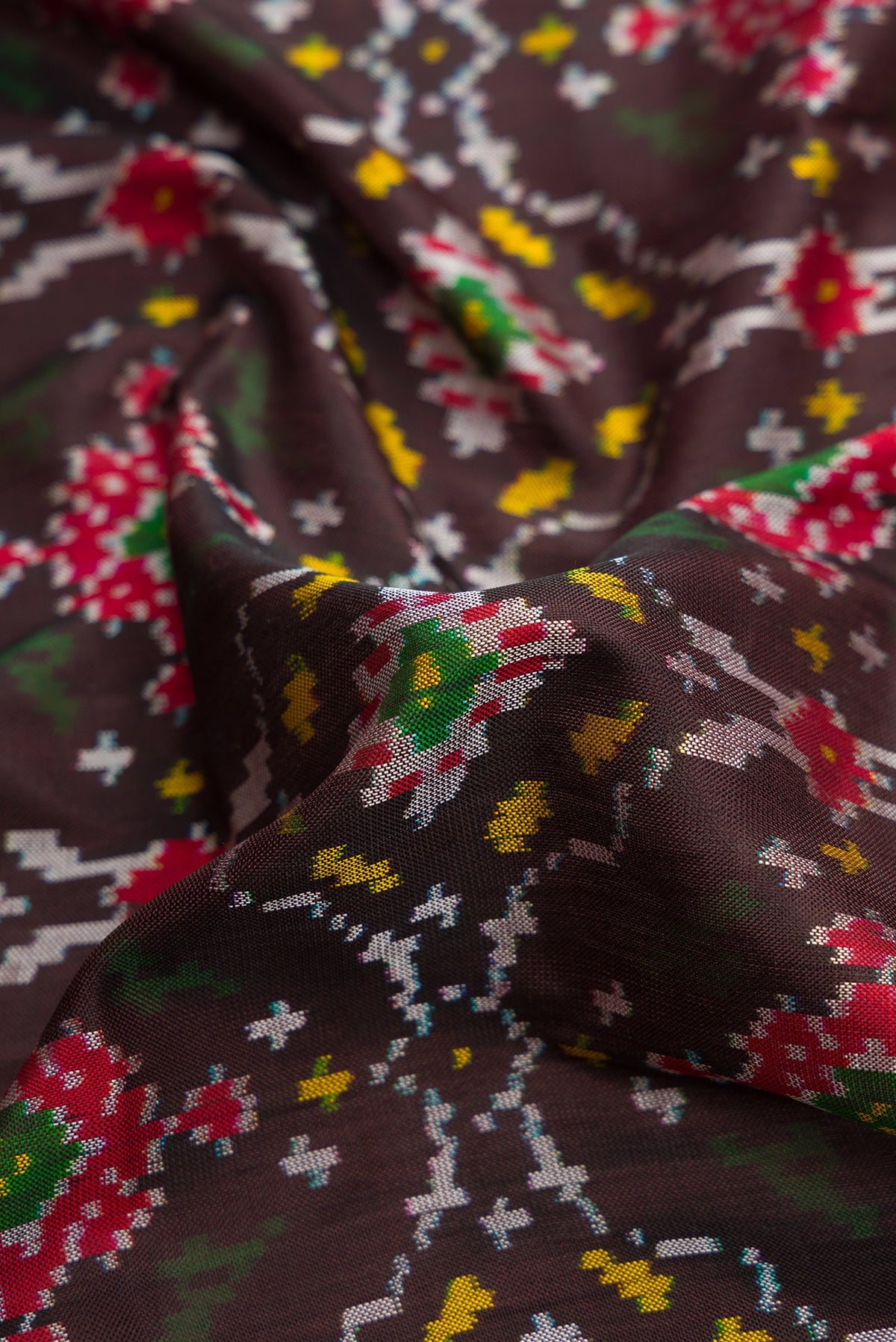 Close up of Black Dual Tone Double Ikat Saree with Ikat Print on the body and Thread Border.  displaying folds