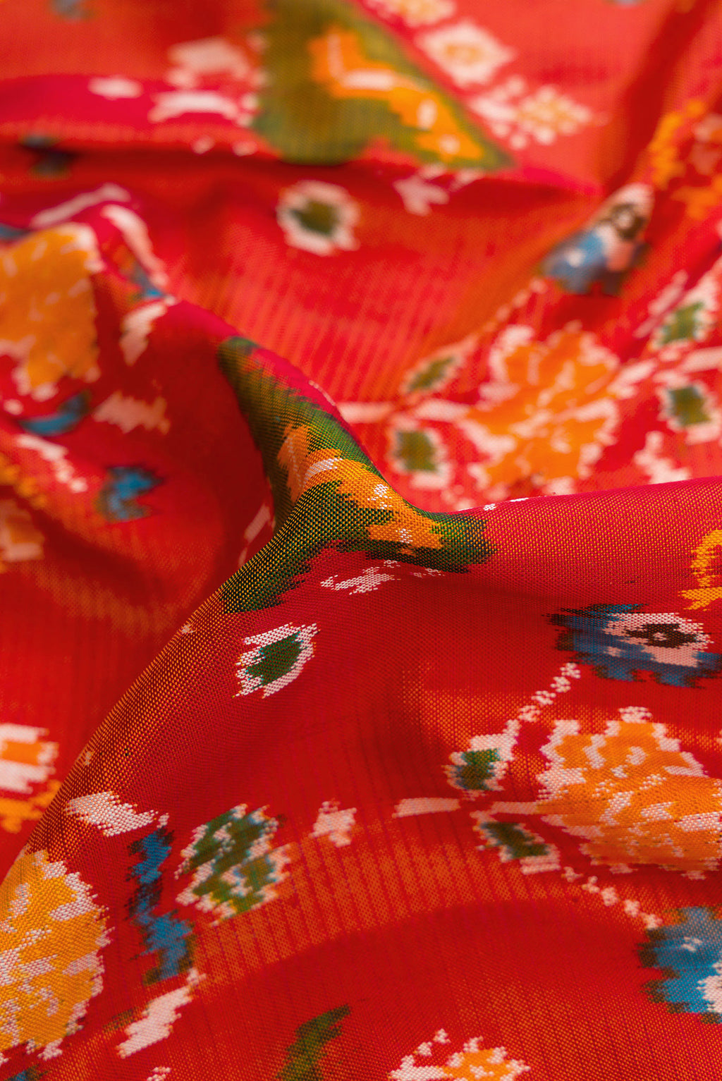 Close up of Brick Orange Dual Tone Double Ikat Saree with Ikat Print on the body and Zari Border.  displaying folds