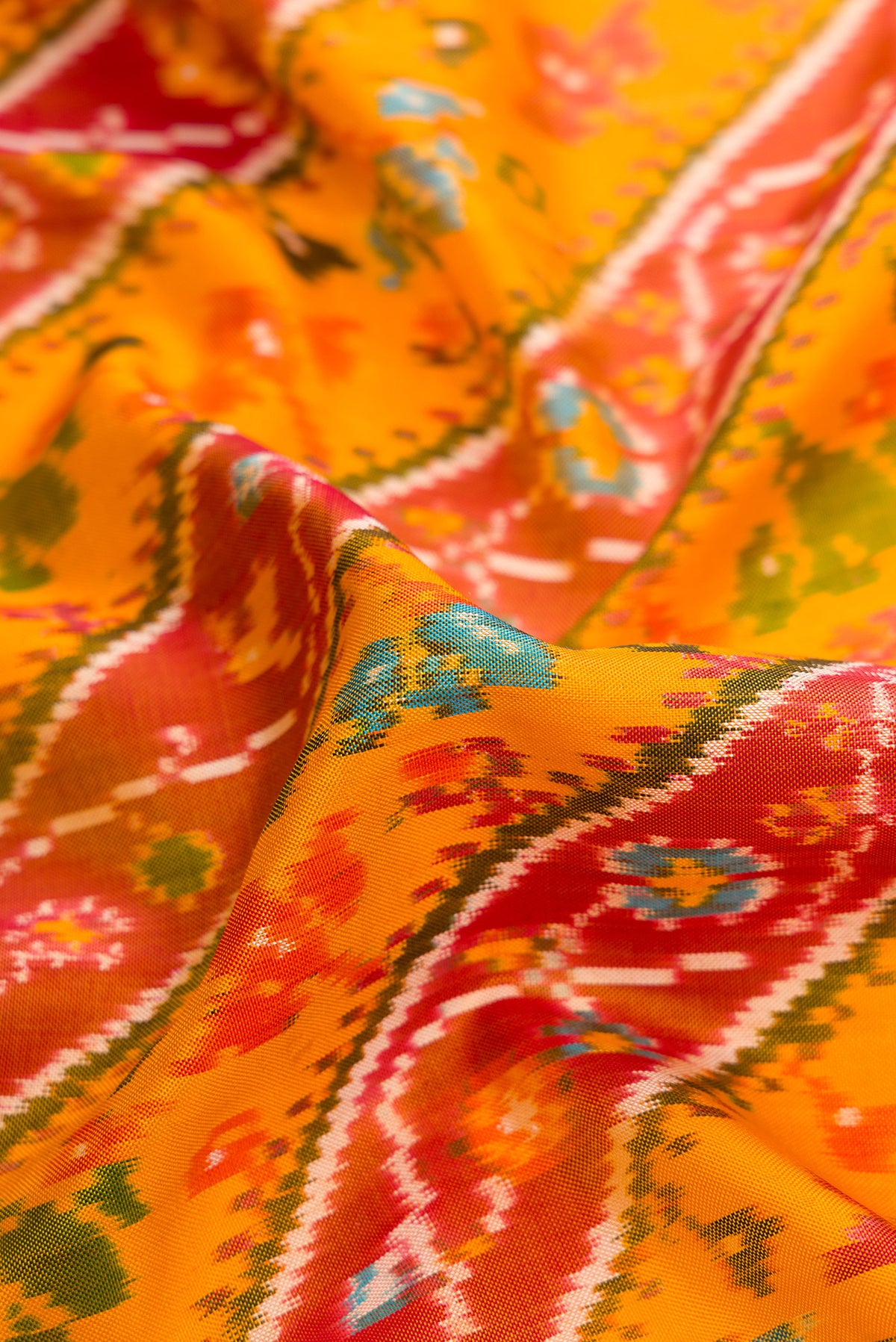 Close up of Mustard Dual Tone Double Ikat Saree with Ikat Print on the body and Ikat Border.  displaying folds
