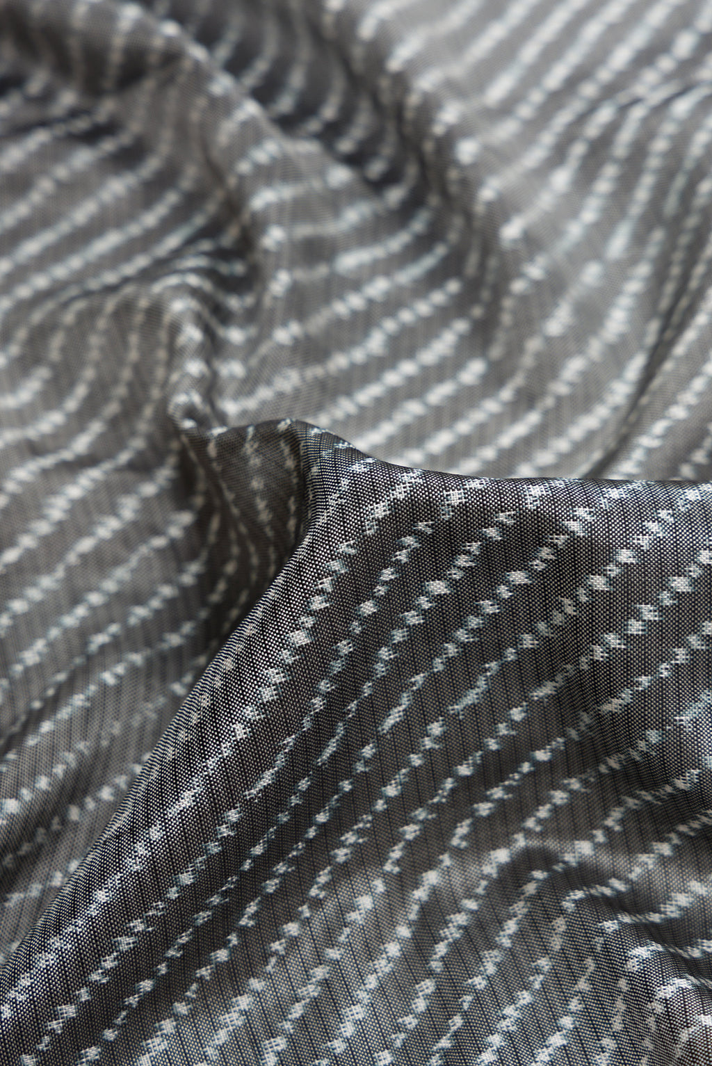 Close up of Grey Dual Tone Double Ikat Saree with Ikat Print on the body and Ikat Border.  displaying folds