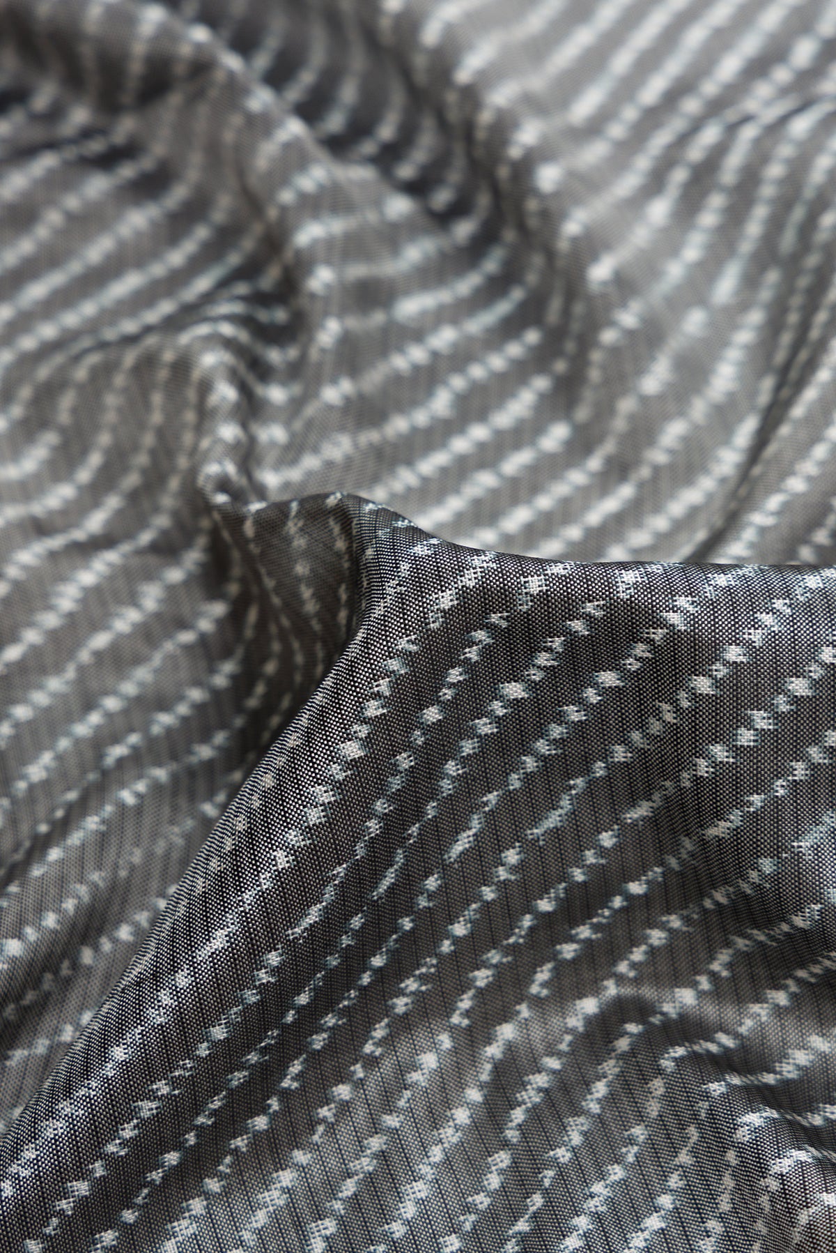 Close up of Grey Dual Tone Double Ikat Saree with Ikat Print on the body and Ikat Border.  displaying folds