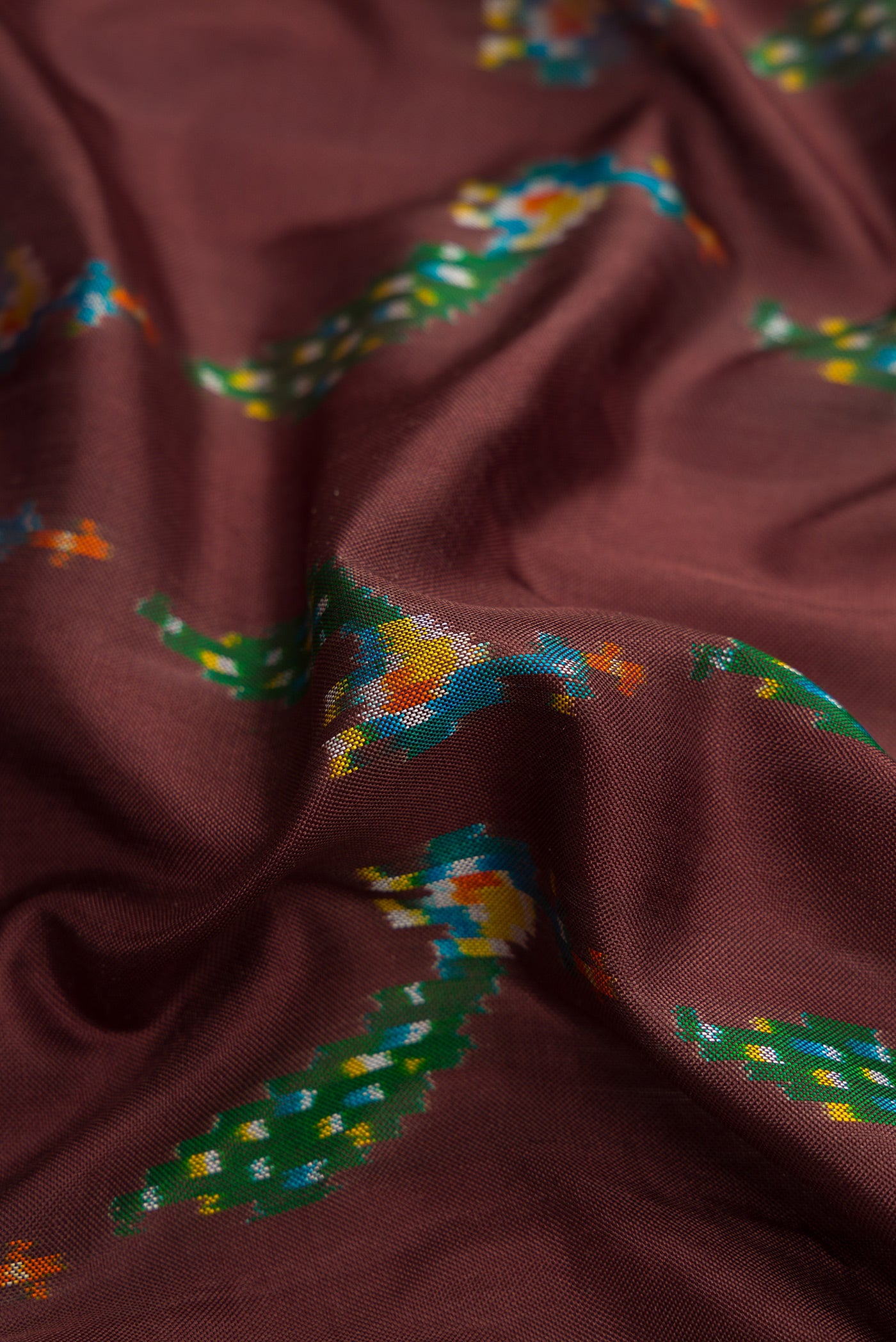Close up of Brown Dual Tone Double Ikat Saree with Ikat Print on the body and Thread Border.  displaying folds