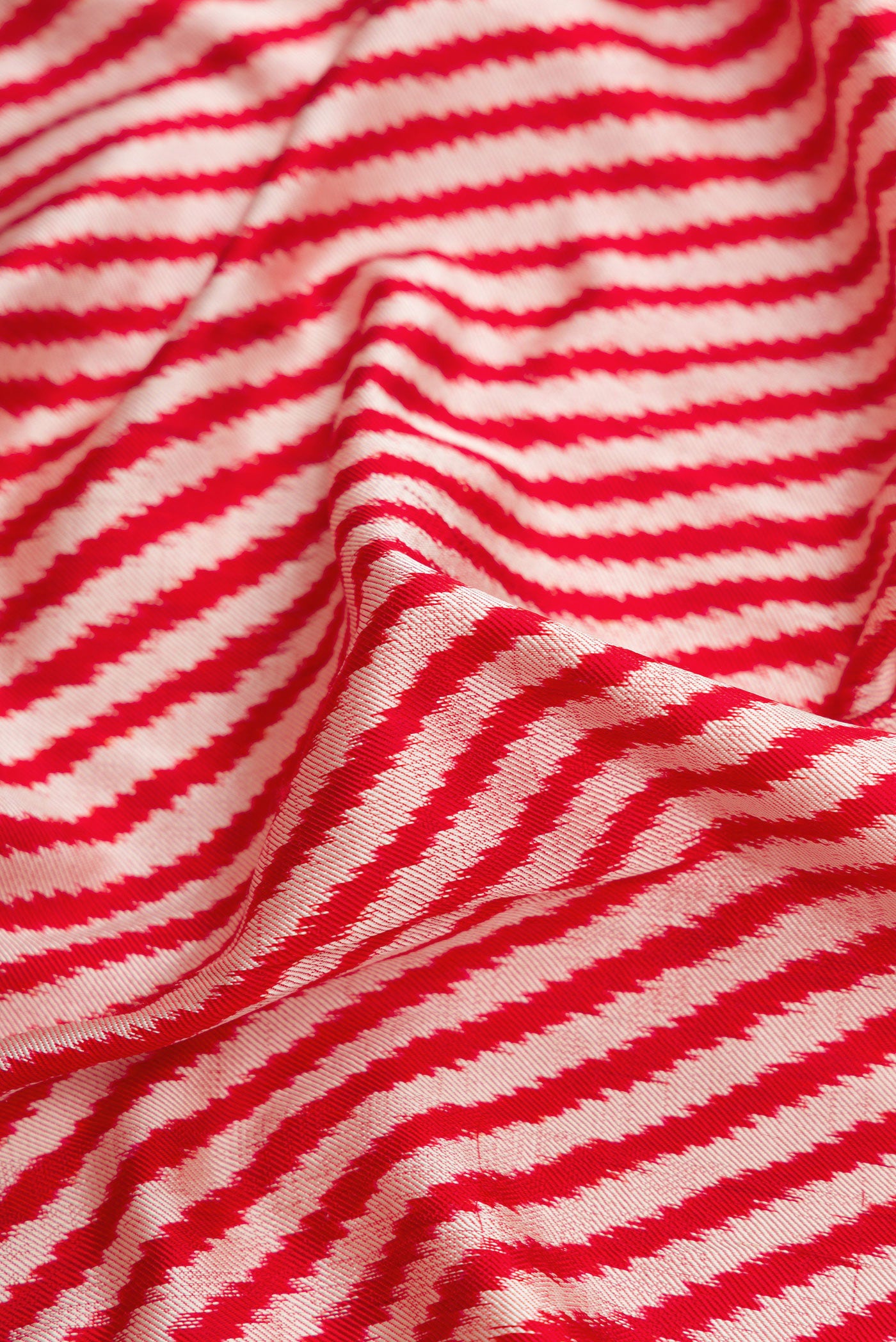 Close up of Red Dual Tone Double Ikat Saree with Ikat Print on the body and Zari Border.  displaying folds