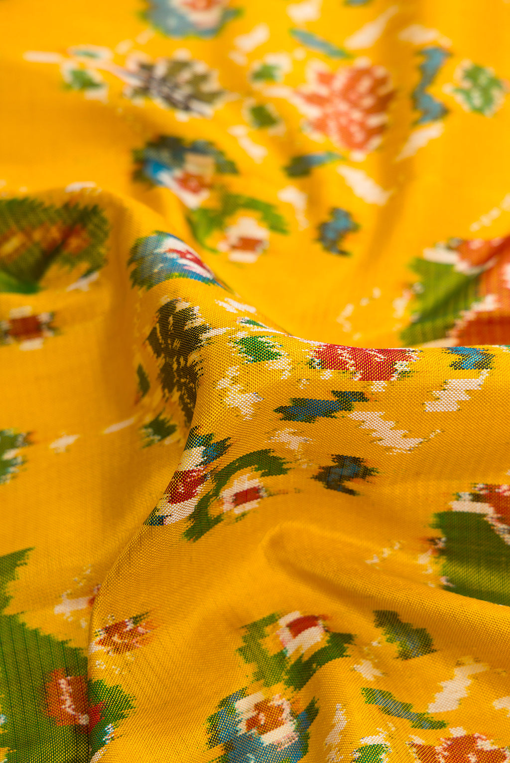 Close up of Mustard Dual Tone Double Ikat Saree with Ikat Print on the body and Ikat Border.  displaying folds