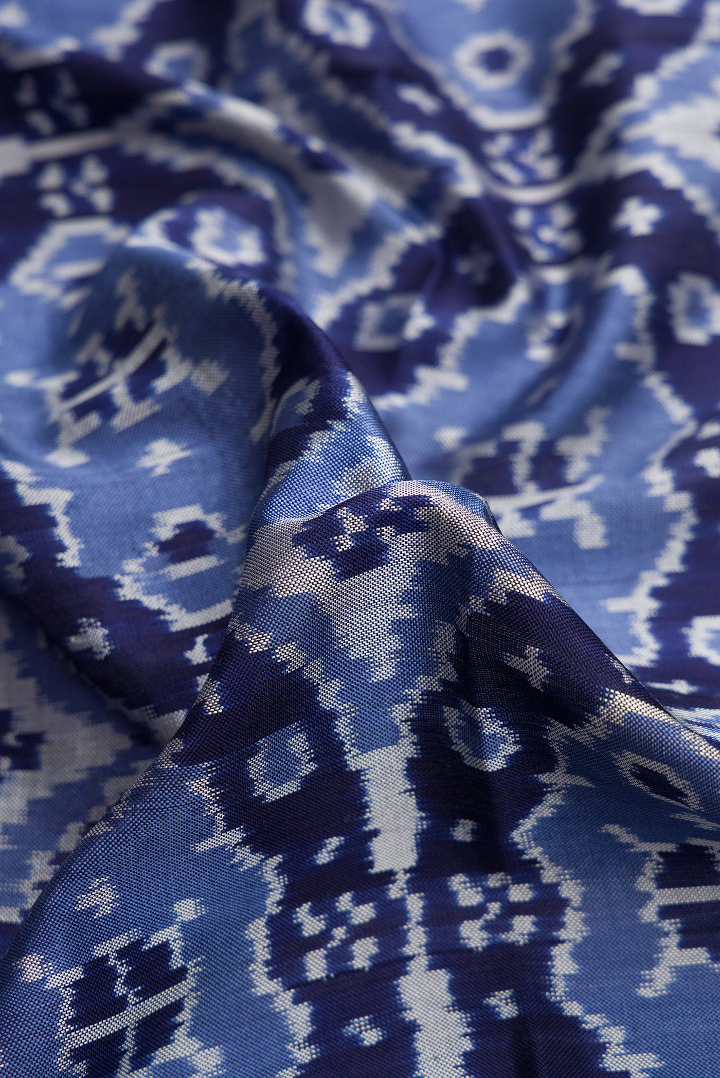 Close up of Navy Blue Dual Tone Double Ikat Saree with Ikat Print on the body and Plain Border.  displaying folds