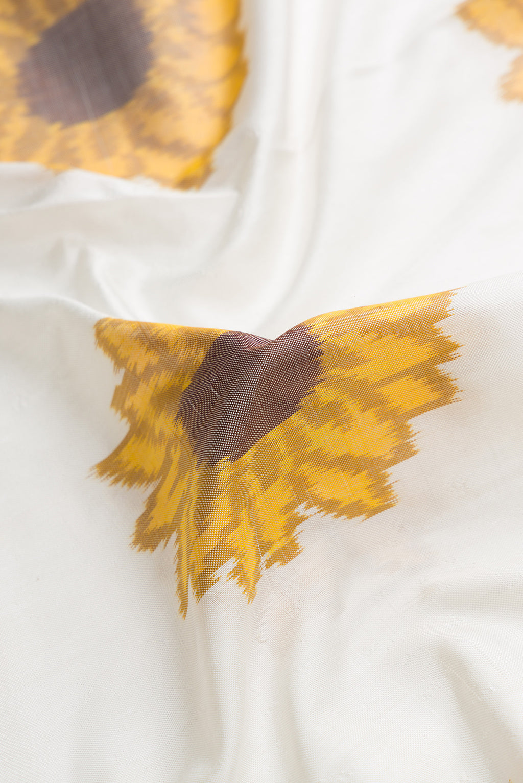 Close up of Off White Dual Tone Double Ikat Saree with Ikat Print on the body and Plain Border.  displaying folds