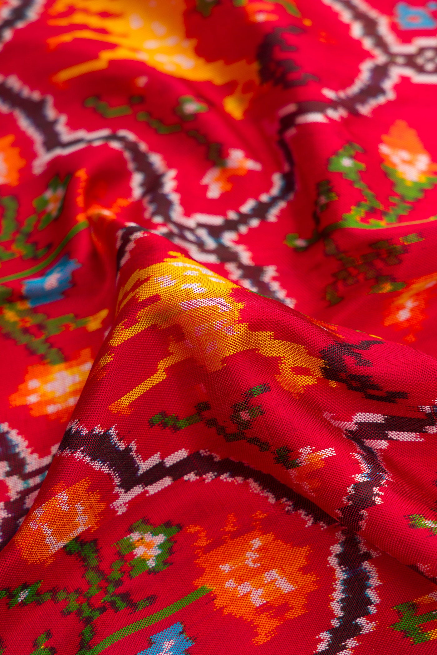 Close up of Red Dual Tone Double Ikat Saree with Ikat Print on the body and Plain Border.  displaying folds