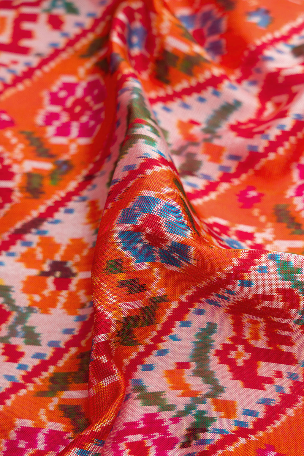 Close up of Brick Orange Dual Tone Double Ikat Saree with Ikat Print on the body and Ikat Border.  displaying folds