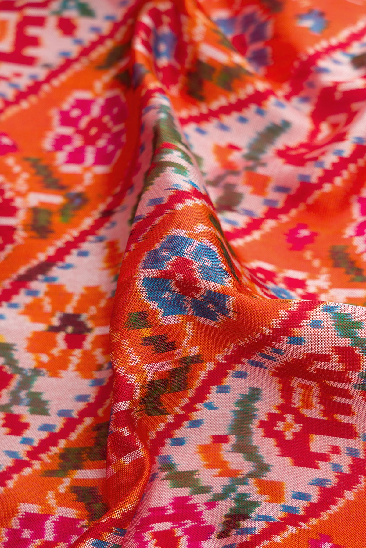 Close up of Brick Orange Dual Tone Double Ikat Saree with Ikat Print on the body and Ikat Border.  displaying folds