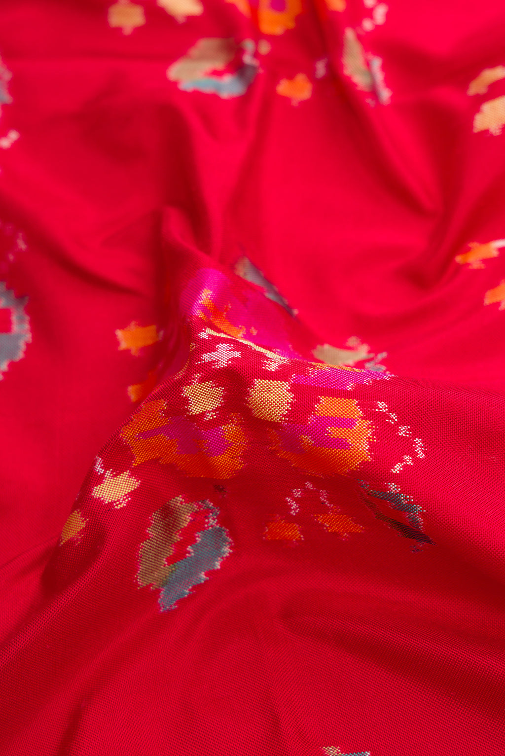 Close up of Red Dual Tone Double Ikat Saree with Ikat Print on the body and Zari Border.  displaying folds
