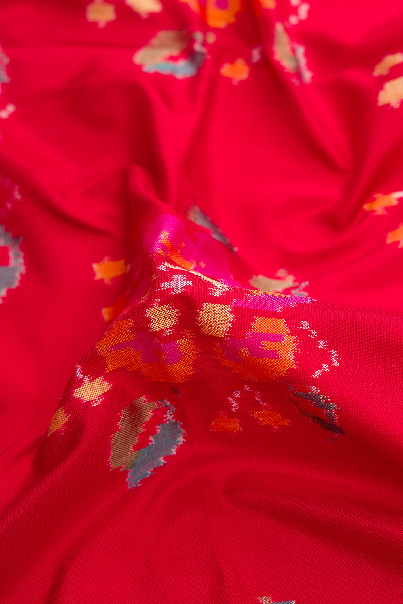 Close up of Red Dual Tone Double Ikat Saree with Ikat Print on the body and Zari Border.  displaying folds