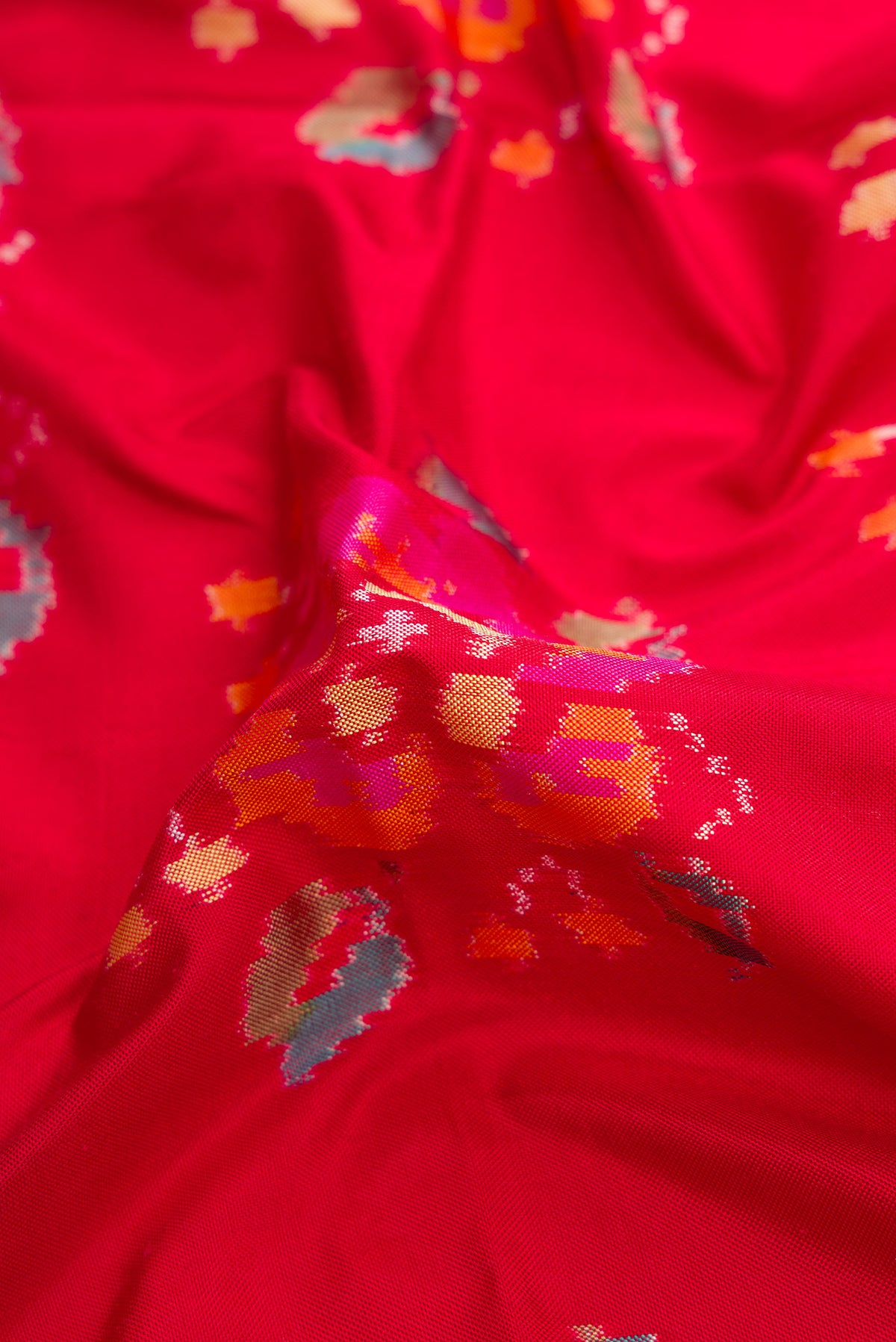 Close up of Red Dual Tone Double Ikat Saree with Ikat Print on the body and Zari Border.  displaying folds