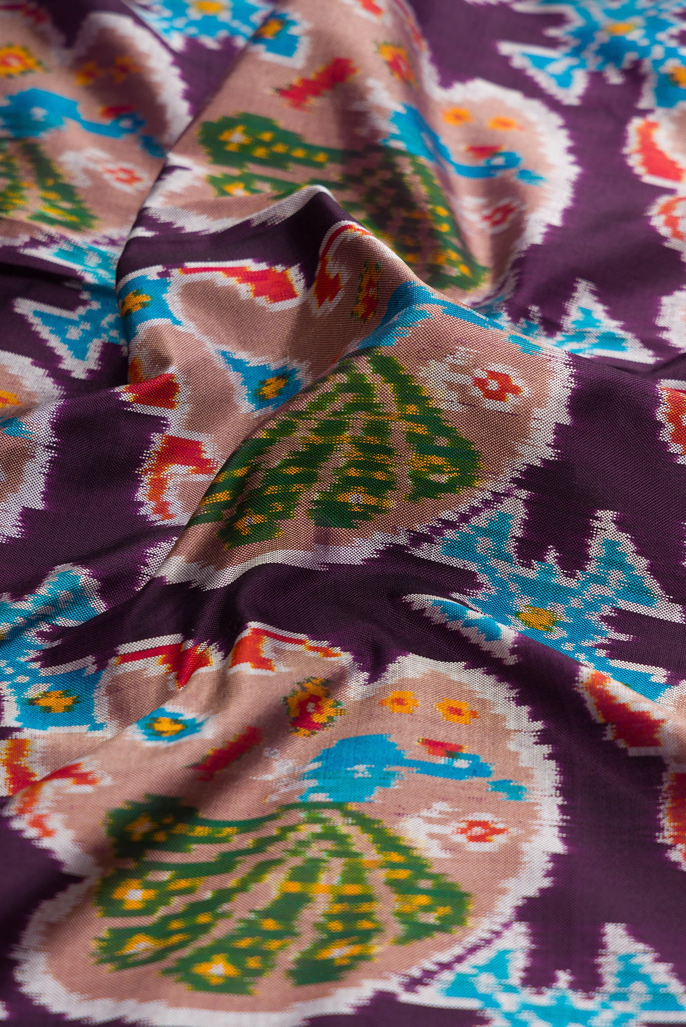 Close up of Burgundy Dual Tone Double Ikat Saree with Ikat Print on the body and Thread Border.  displaying folds