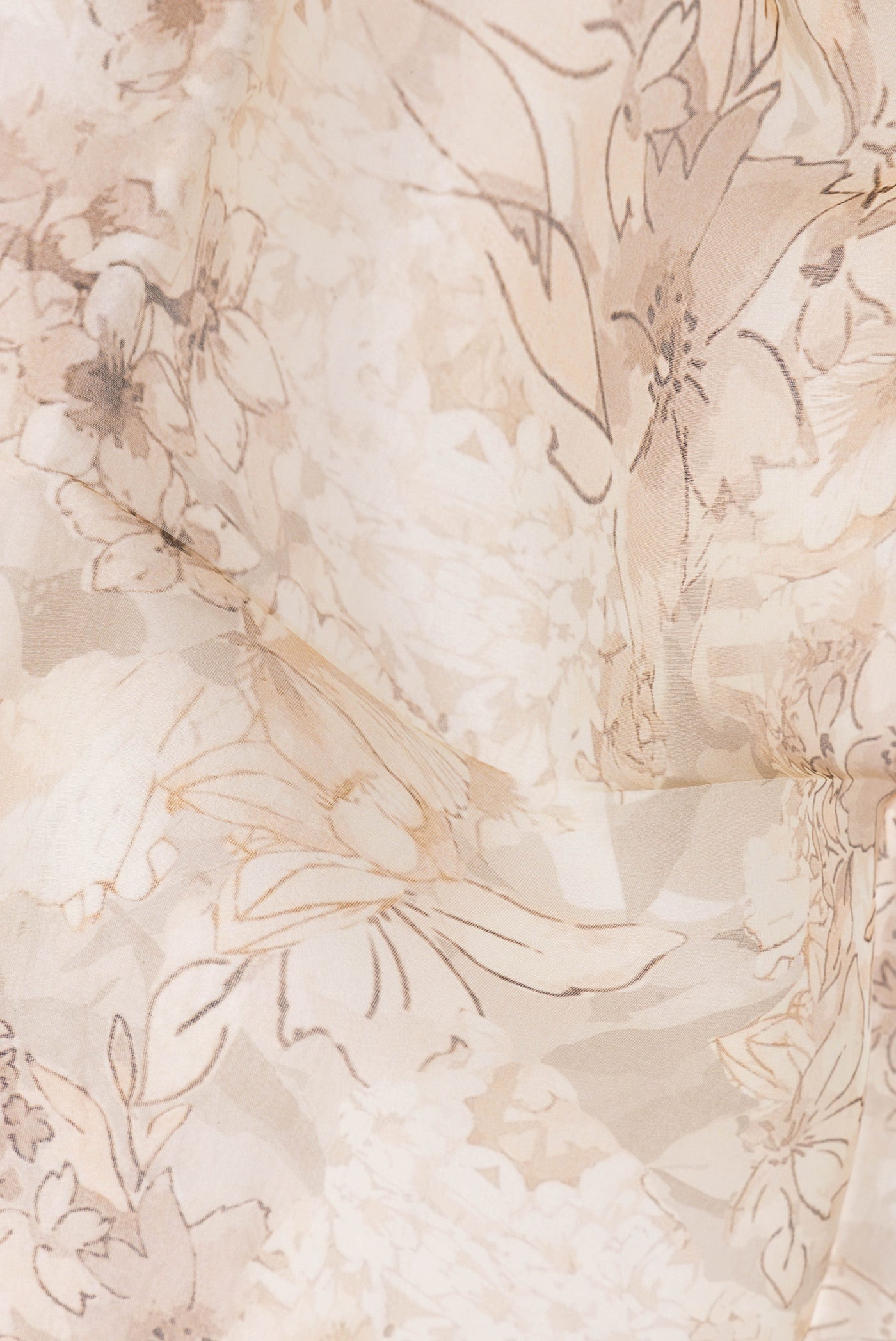 Close up of Beige Organza Silk Saree with Floral Print on the body and Satin Border.  displaying folds