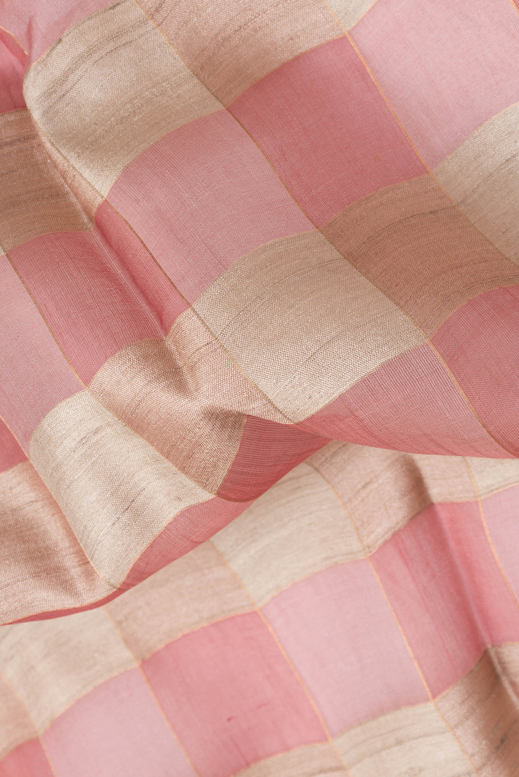 Close up of Beige and Pink Color Tussar Silk Saree with Checked design on the body and Zari Border.  displaying folds