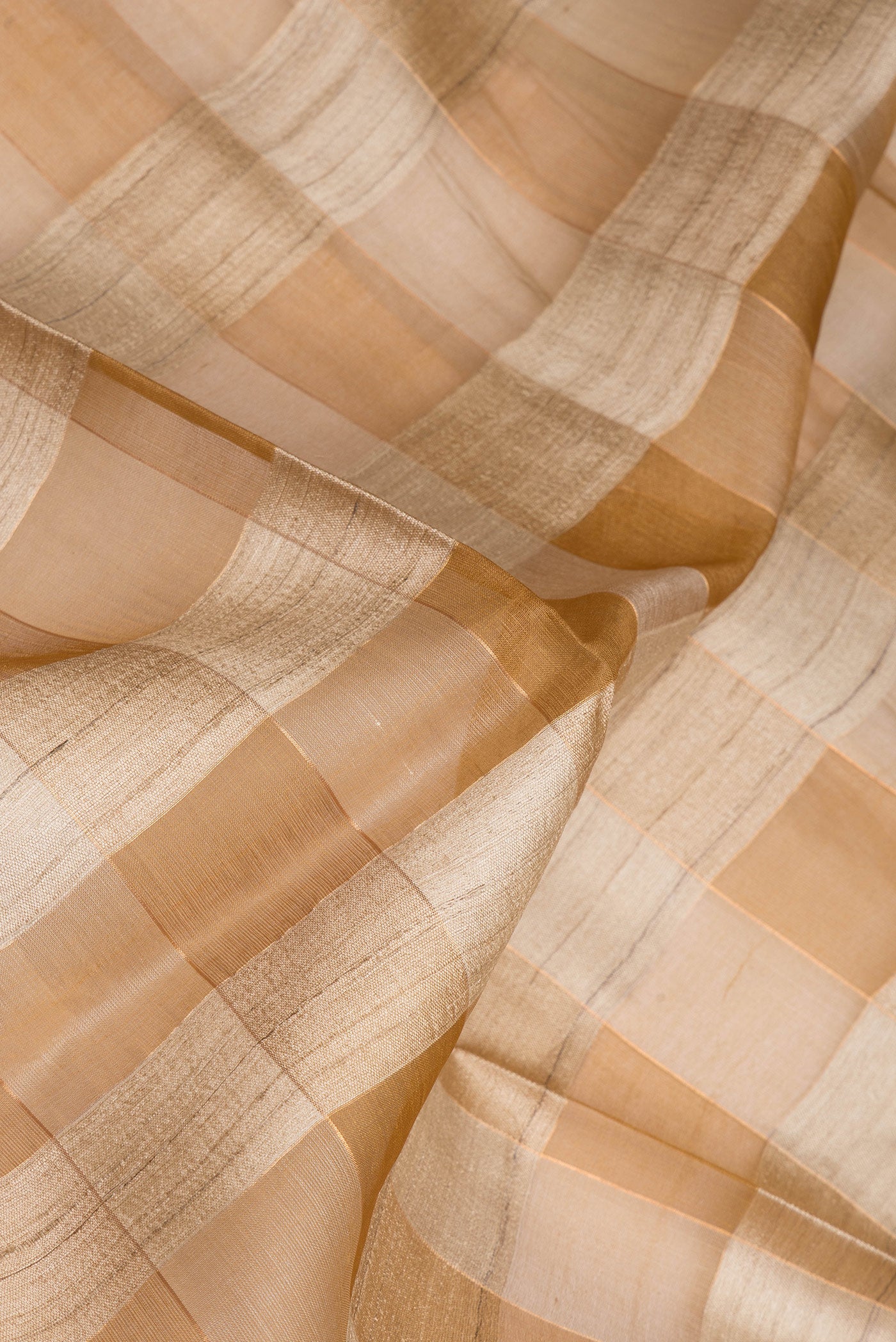 Close up of Beige Tussar Silk Saree with Checked design on the body and Without Border.  displaying folds