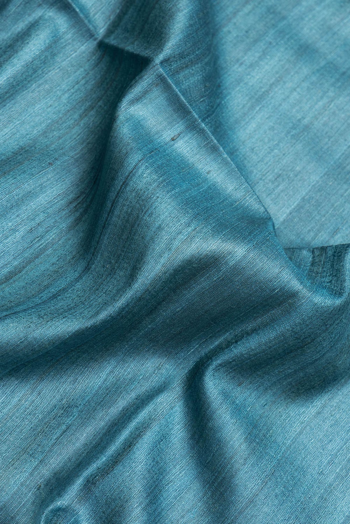 Close up of Sky Blue Dual Tone Tussar Silk Saree with Plain Body and Fancy Border.  displaying folds