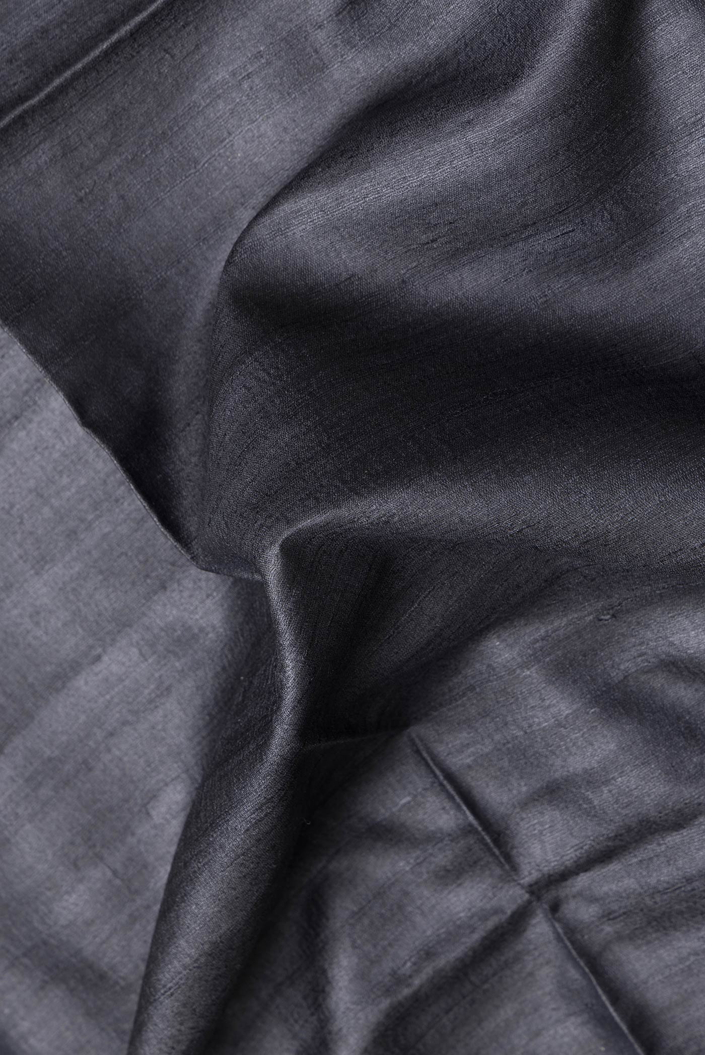 Close up of Black Dual Tone Tussar Silk Saree with Plain Body and Fancy Border.  displaying folds