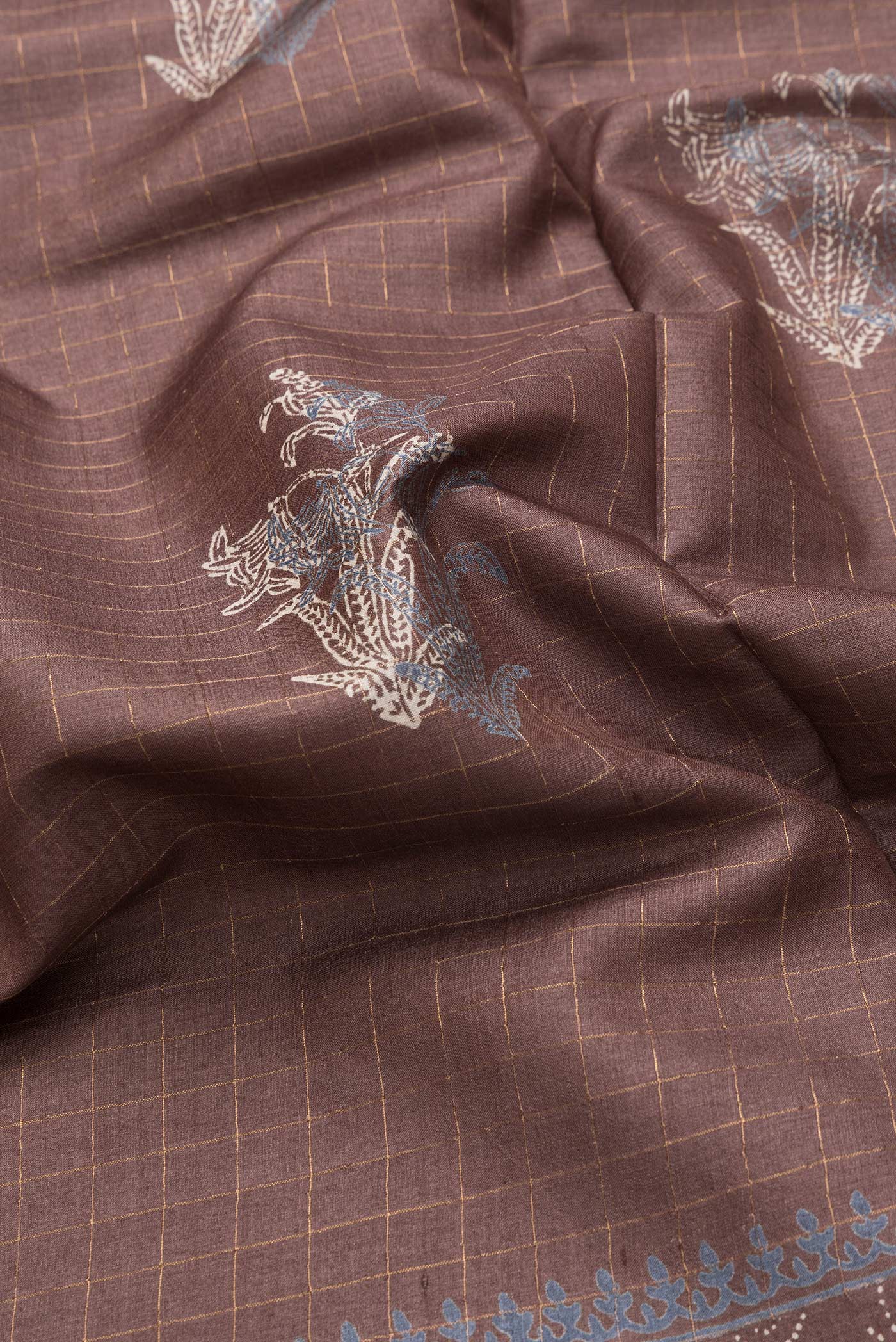 Close up of Brown Dual Tone Tussar Silk Saree with Checked design on the body and Printed Border.  displaying folds
