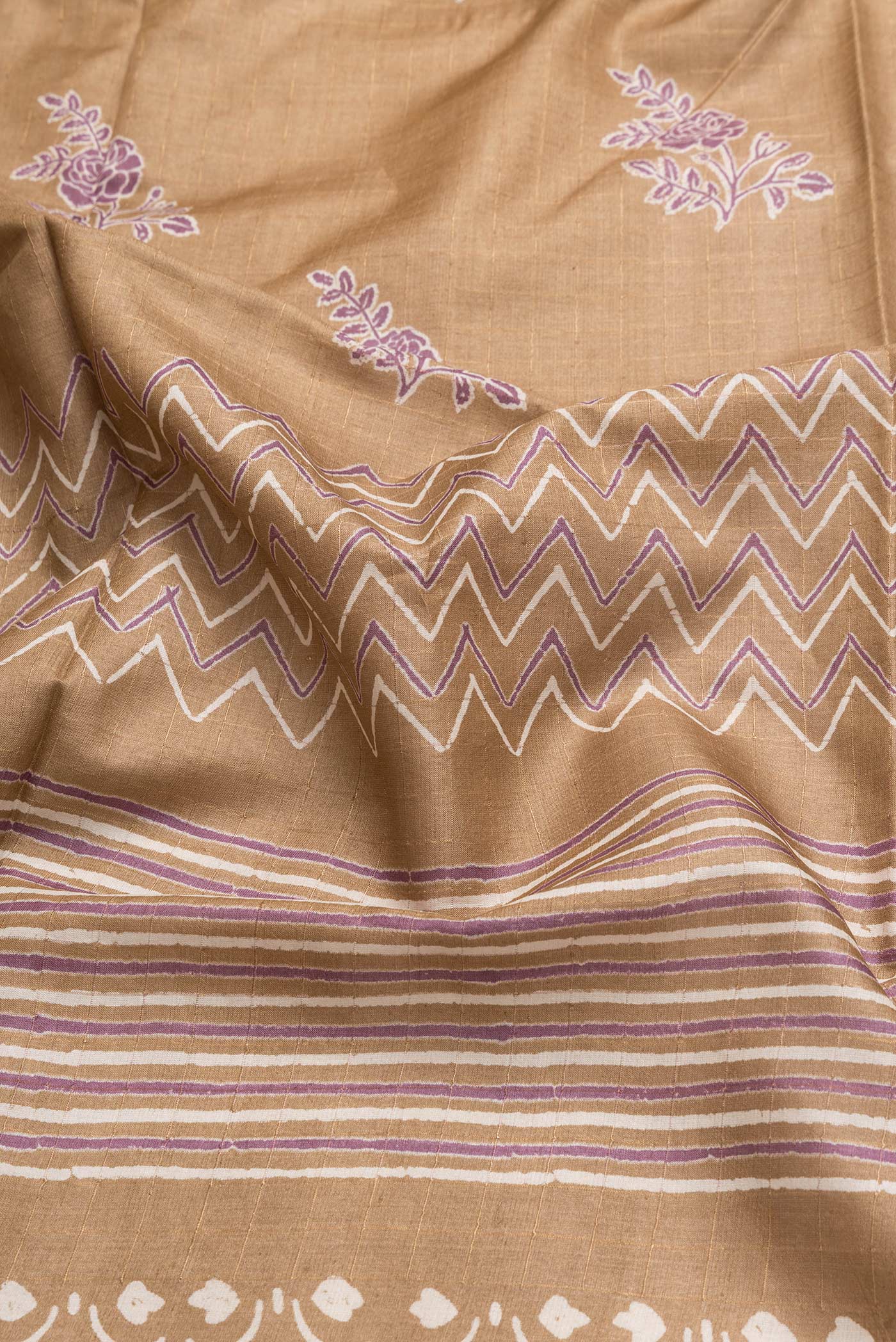 Close up of Caramel Dual Tone Tussar Silk Saree with Printed design on the body and Printed Border.  displaying folds