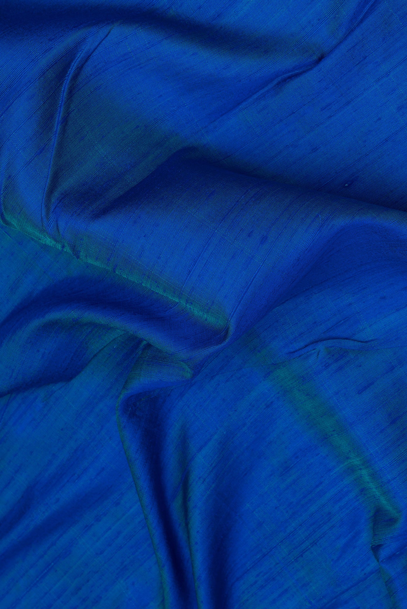 Close up of Peacock Blue Dual Tone Tussar Silk Saree with Plain Body and Printed Border.  displaying folds