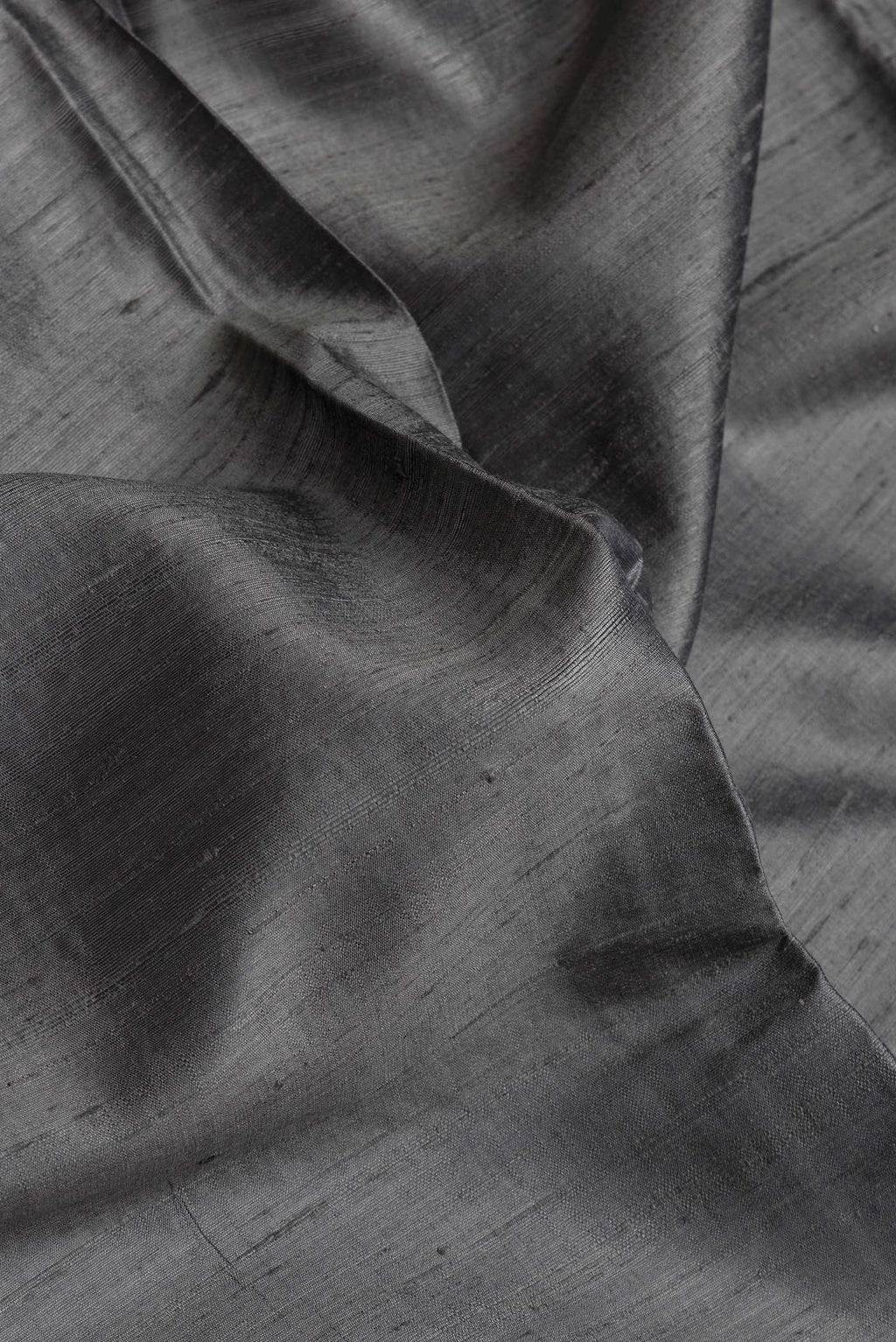 Close up of Grey Dual Tone Raw Silk Saree with Plain Body and Thin Zari Line.  displaying folds