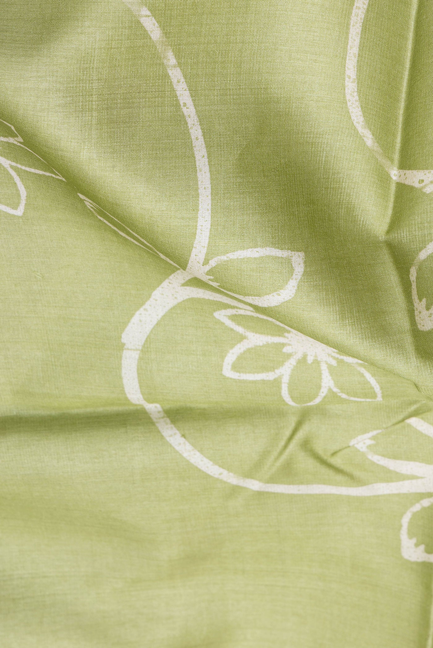 Close up of Pista Green Tussar Silk Saree with Printed design on the body and Plain Border.  displaying folds