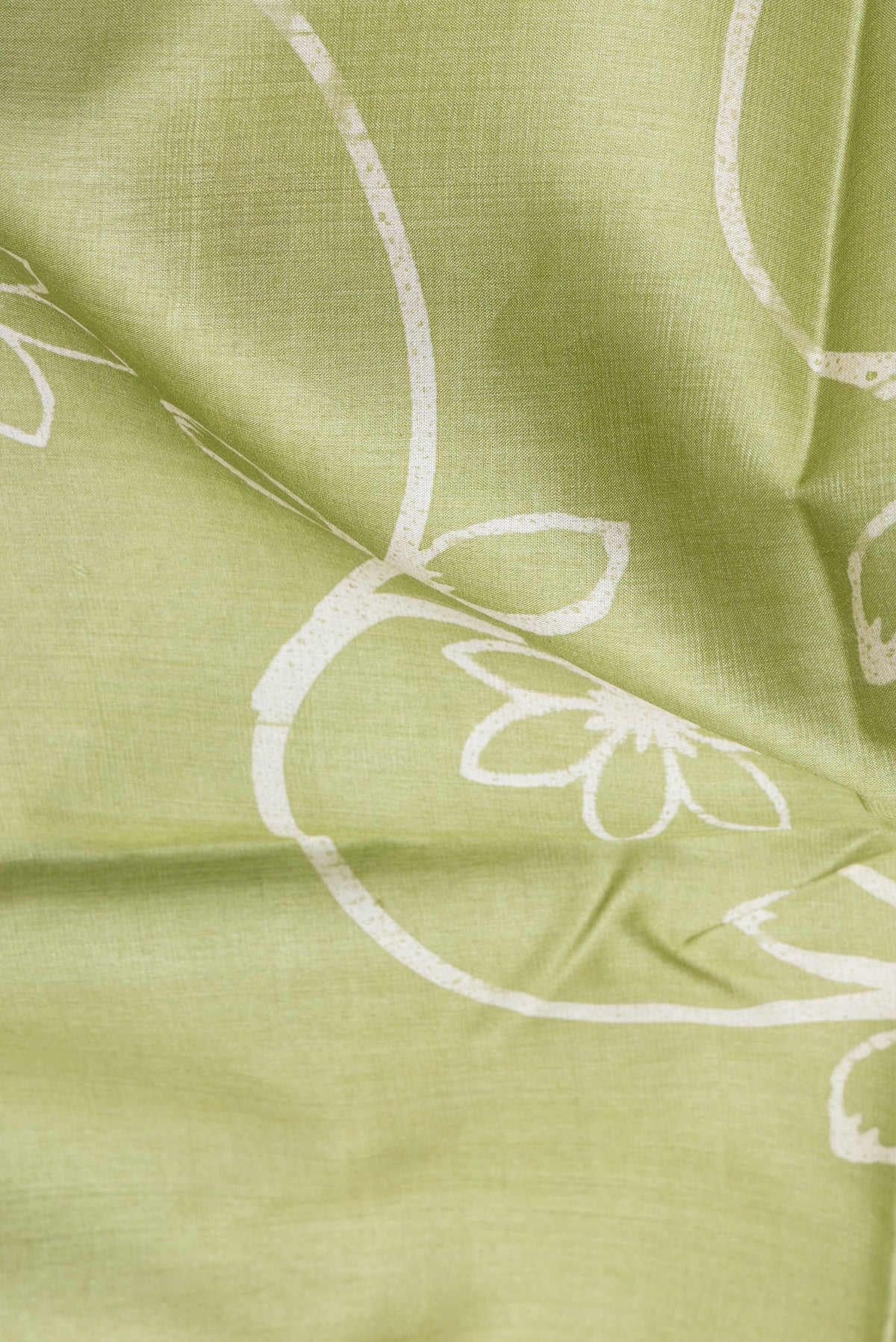Close up of Pista Green Tussar Silk Saree with Printed design on the body and Plain Border.  displaying folds