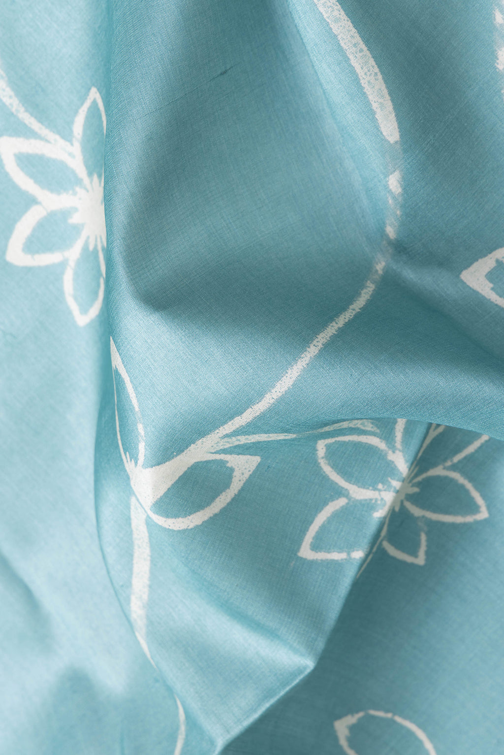 Close up of Sky Blue Dual Tone Tussar Silk Saree with Printed design on the body and Plain Border.  displaying folds