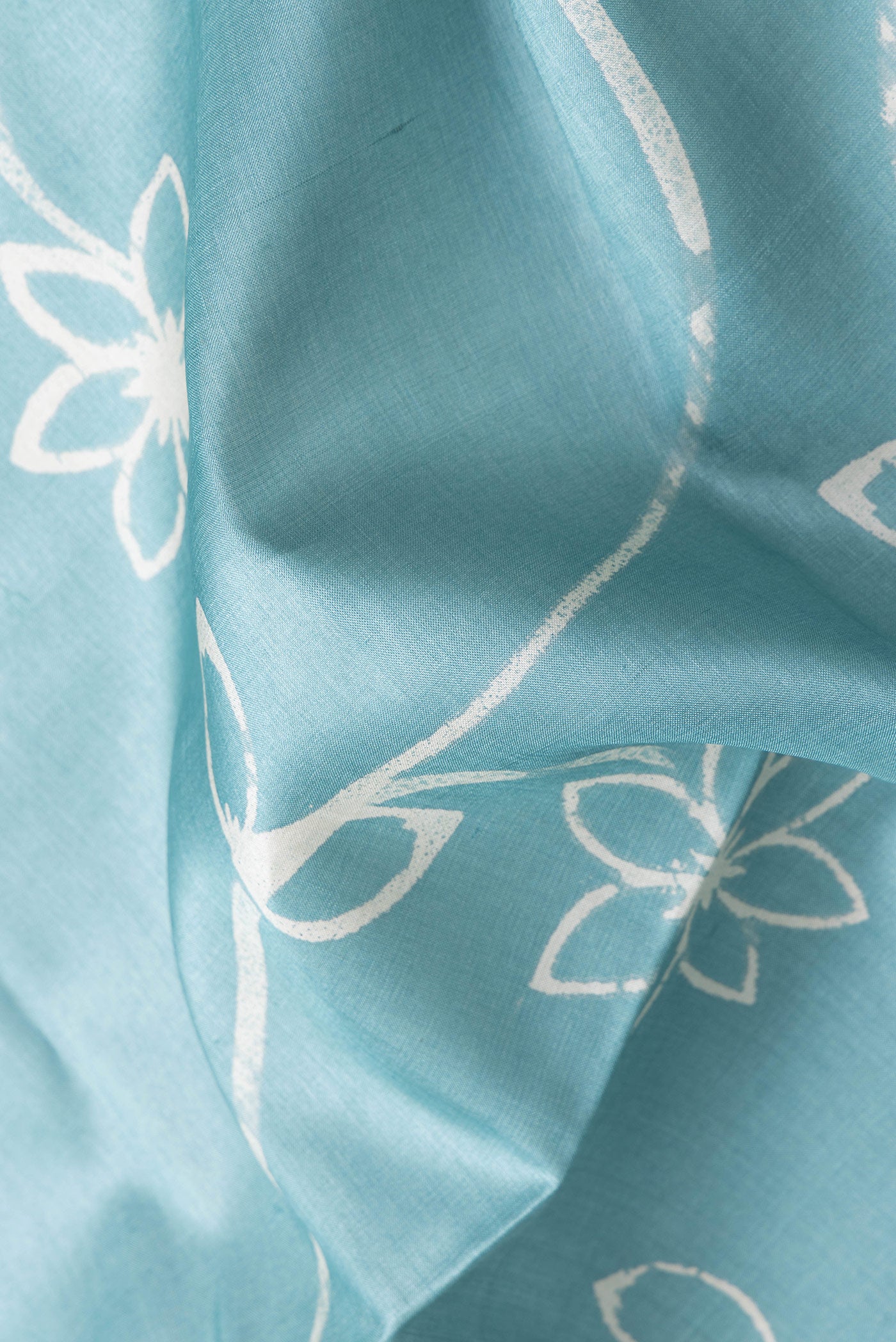 Close up of Sky Blue Dual Tone Tussar Silk Saree with Printed design on the body and Plain Border.  displaying folds