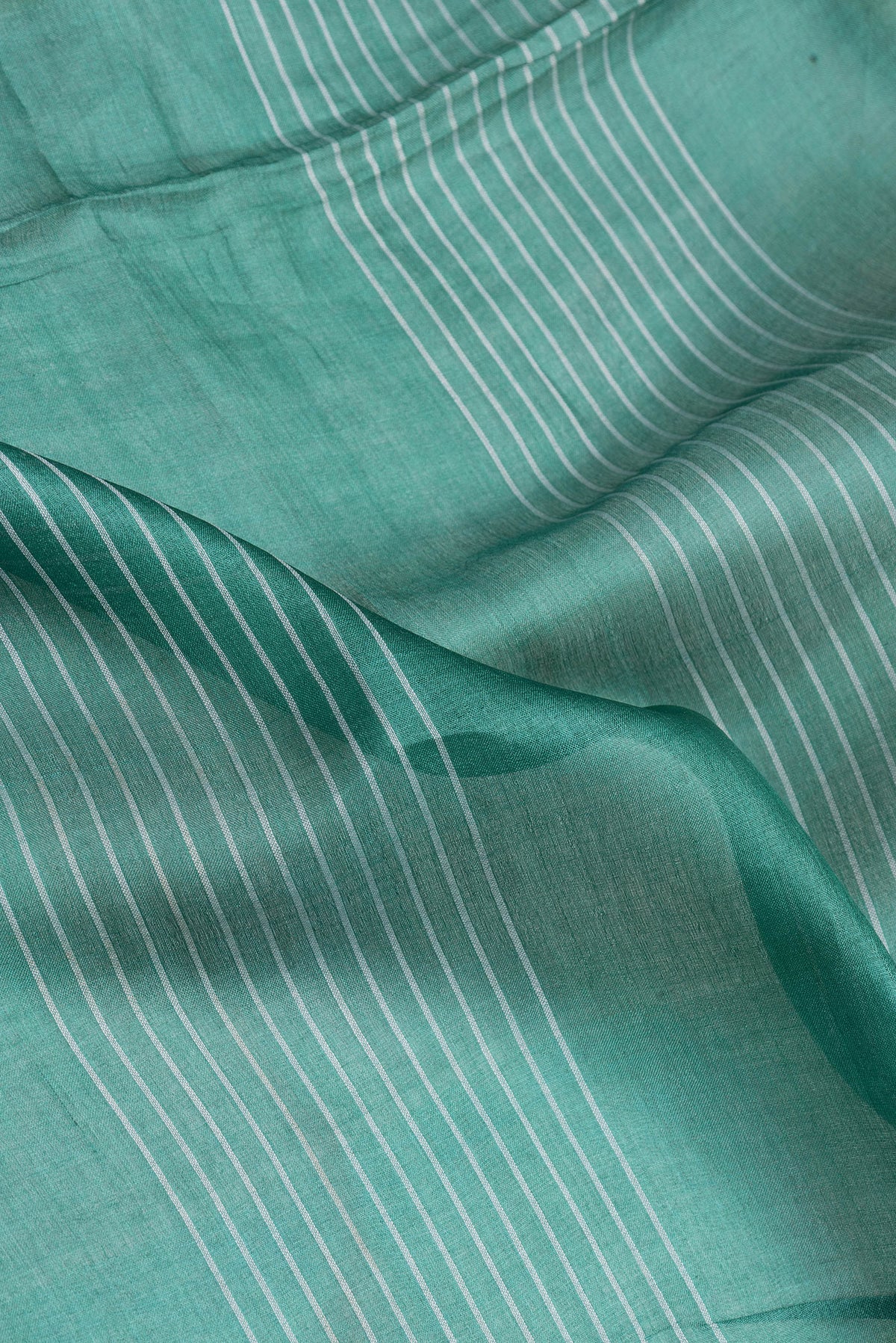 Close up of Green Tussar Silk Saree with Stripes on the body and Printed Border.  displaying folds