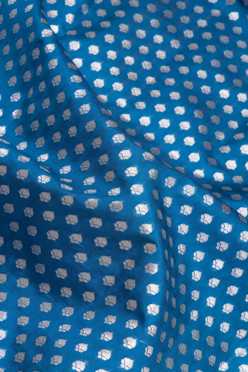 Close up of Peacock Blue Dual Tone Tussar Silk Saree with Zari Butta on the body and Zari Border.  displaying folds