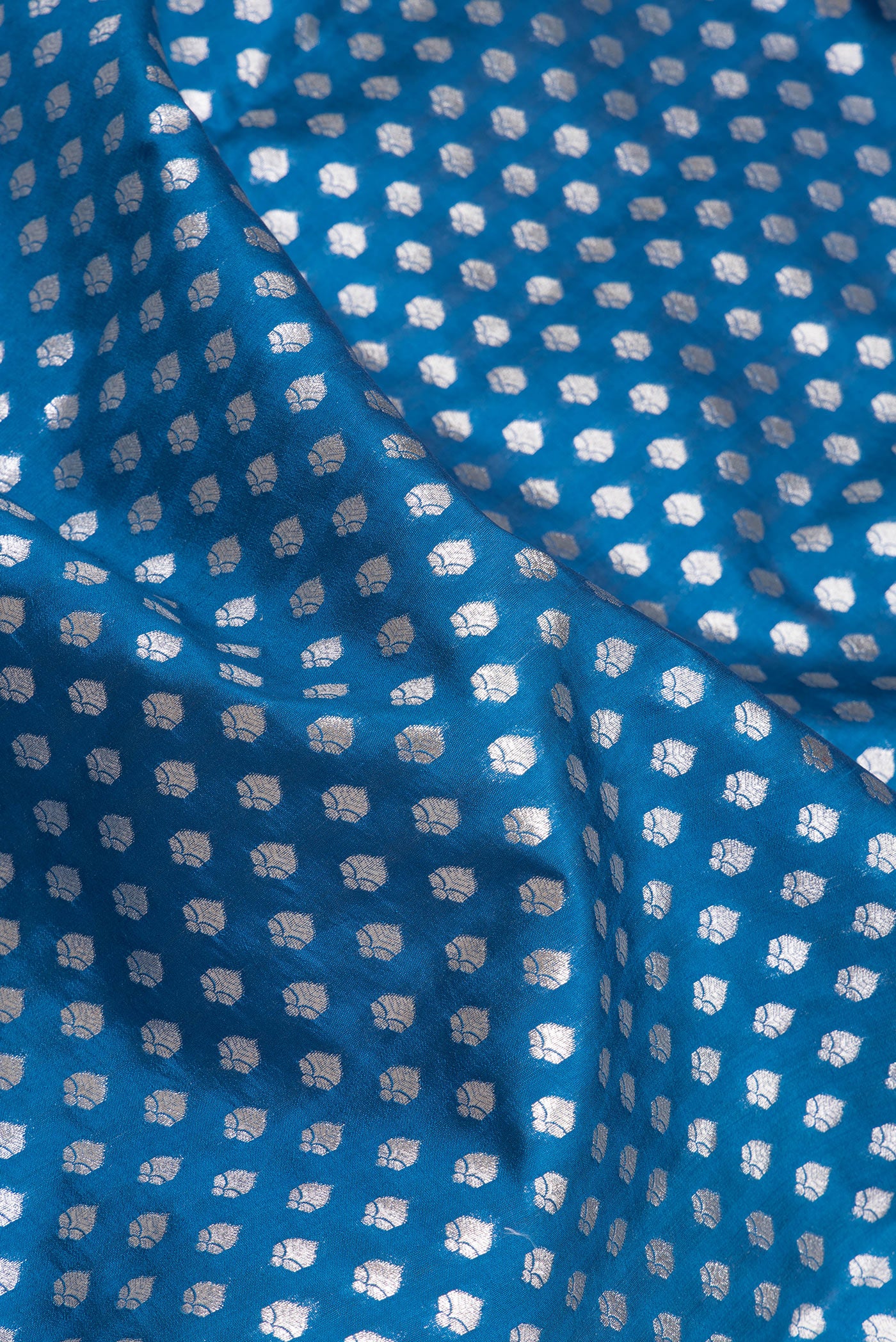 Close up of Peacock Blue Dual Tone Tussar Silk Saree with Zari Butta on the body and Zari Border.  displaying folds