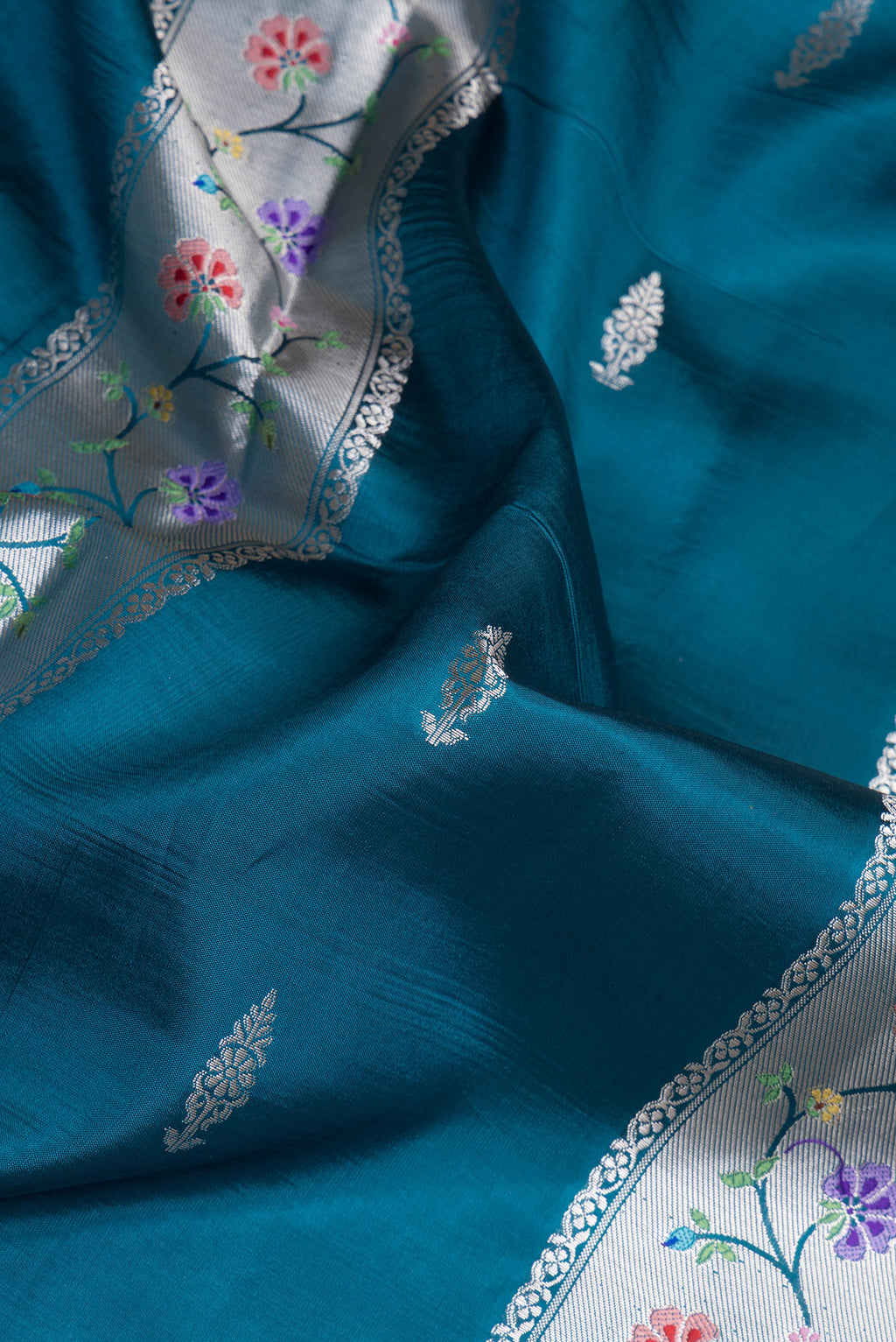 Close up of Peacock Blue Dual Tone Tussar Silk Saree with Zari Butta on the body and Zari Border.  displaying folds