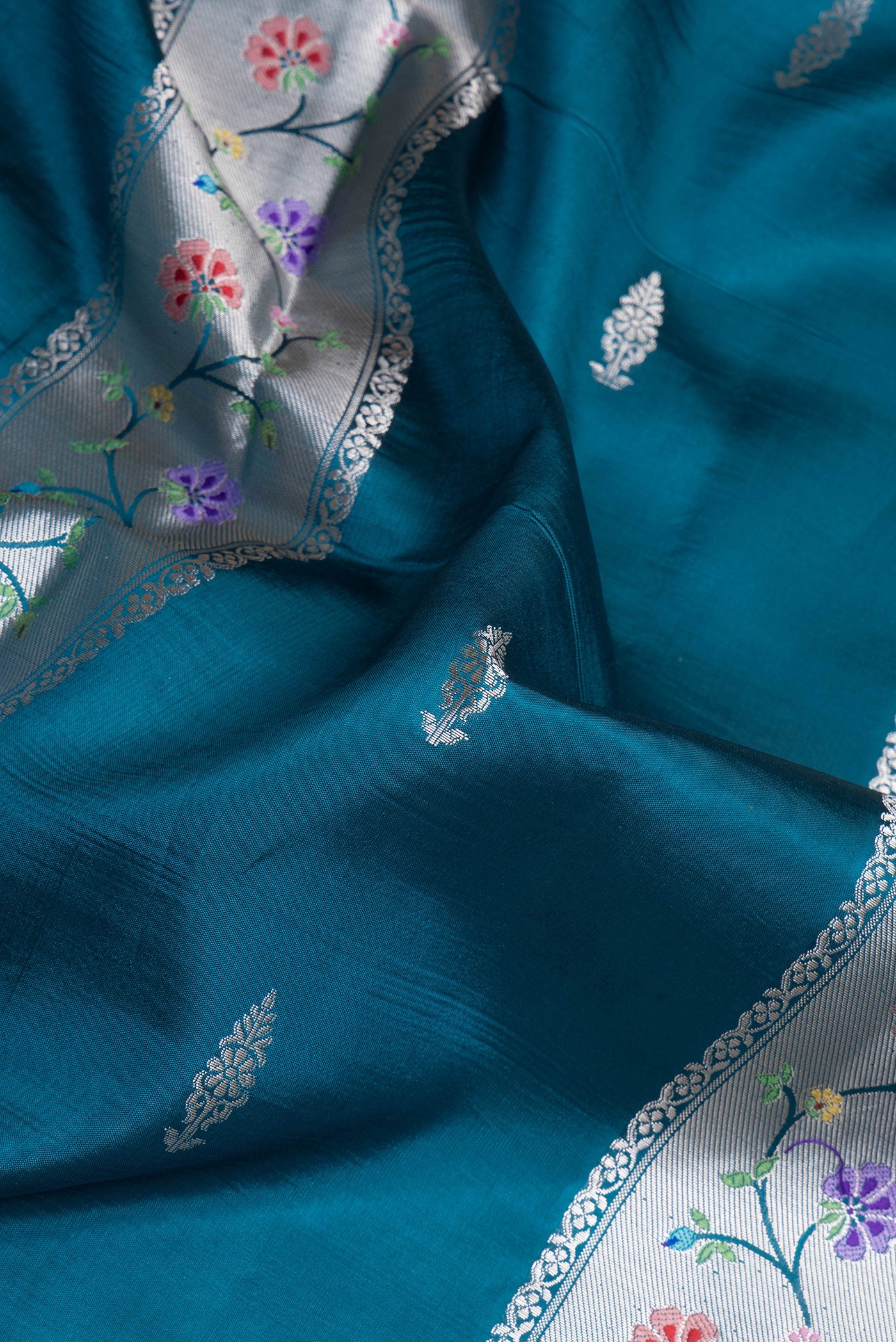 Close up of Peacock Blue Dual Tone Tussar Silk Saree with Zari Butta on the body and Zari Border.  displaying folds
