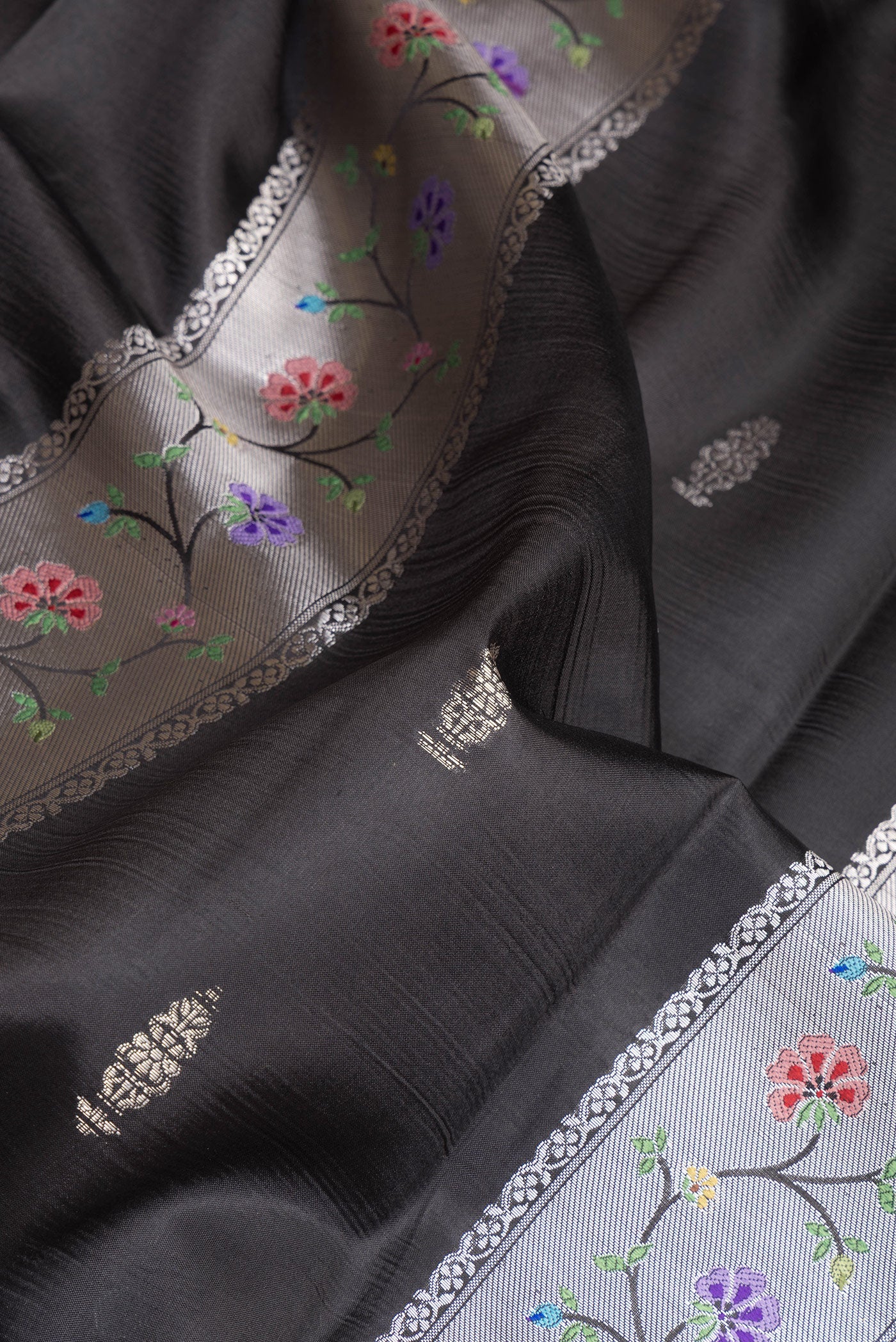 Close up of Black Dual Tone Tussar Silk Saree with Zari Butta on the body and Zari Border.  displaying folds