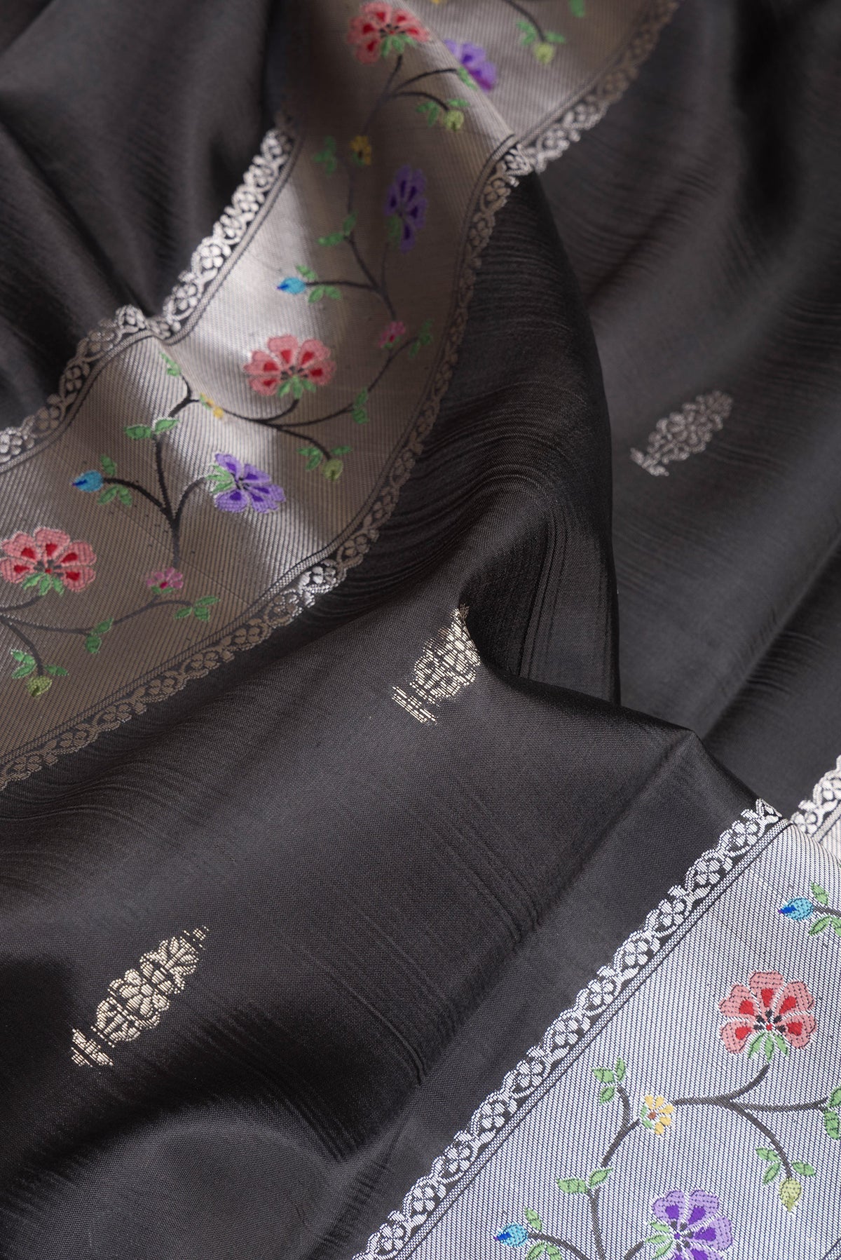 Close up of Black Dual Tone Tussar Silk Saree with Zari Butta on the body and Zari Border.  displaying folds