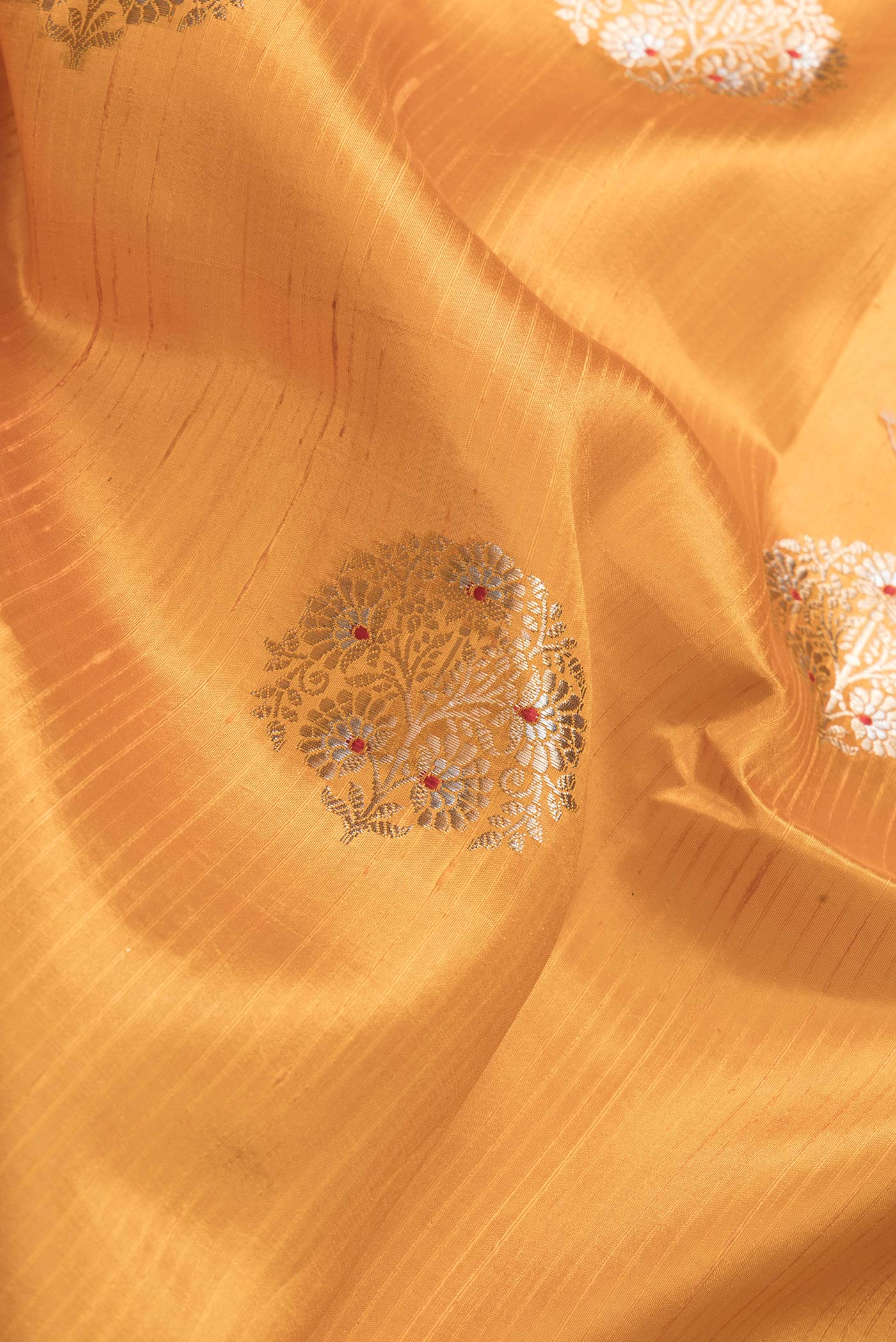 Close up of Mustard Dual Tone Tussar Silk Saree with Zari Butta on the body and Fancy Border.  displaying folds