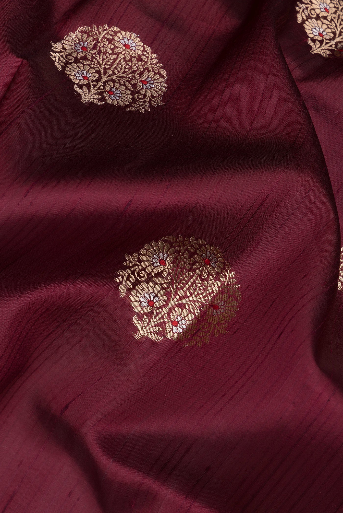 Close up of Coffee Brown Tussar Silk Saree with Zari And Thread Butta on the body and Zari Border.  displaying folds
